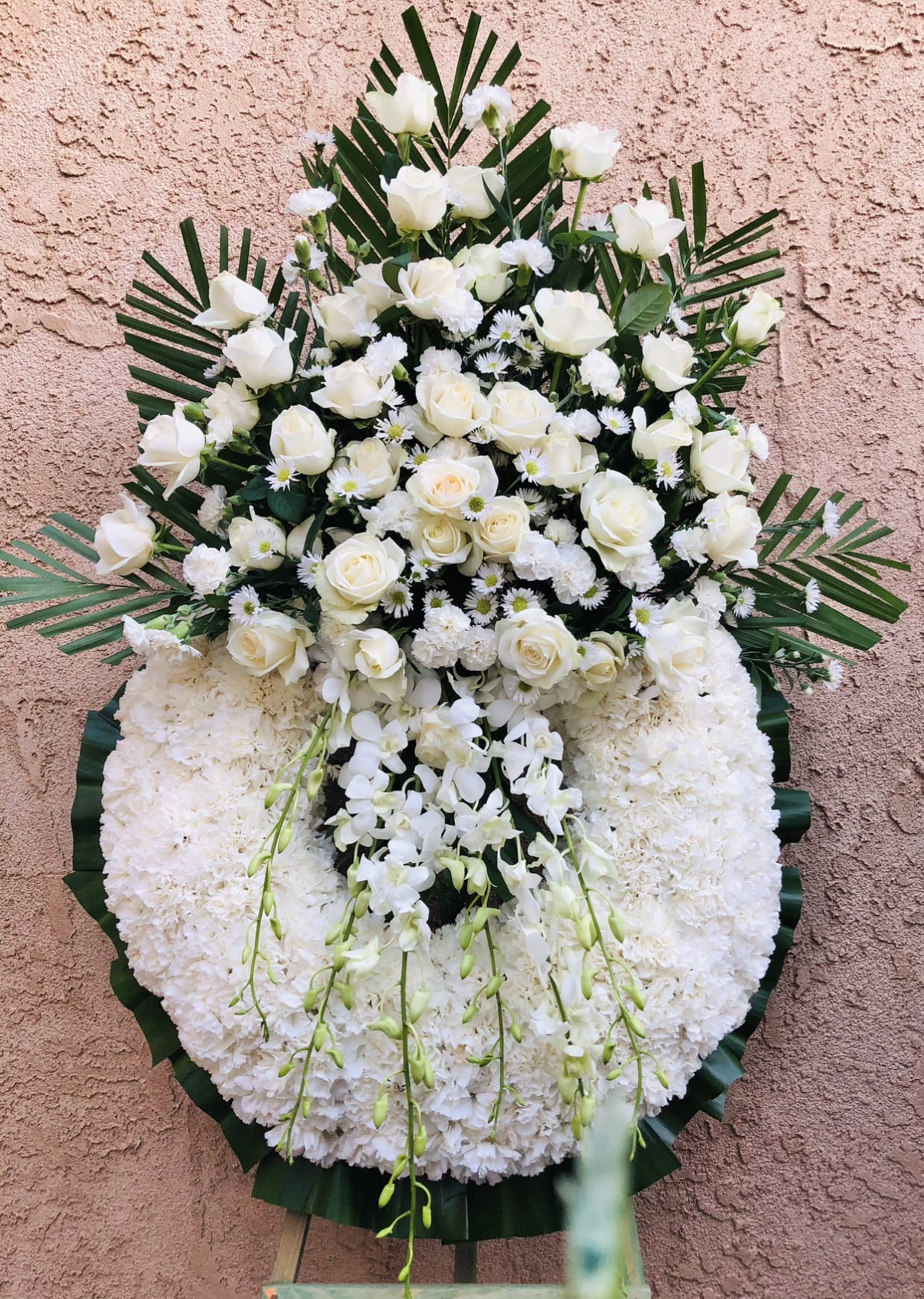Sky light - Beautiful white and green standing funeral spray arrangement featuring carnations, roses, daises, orchids, and green accents.