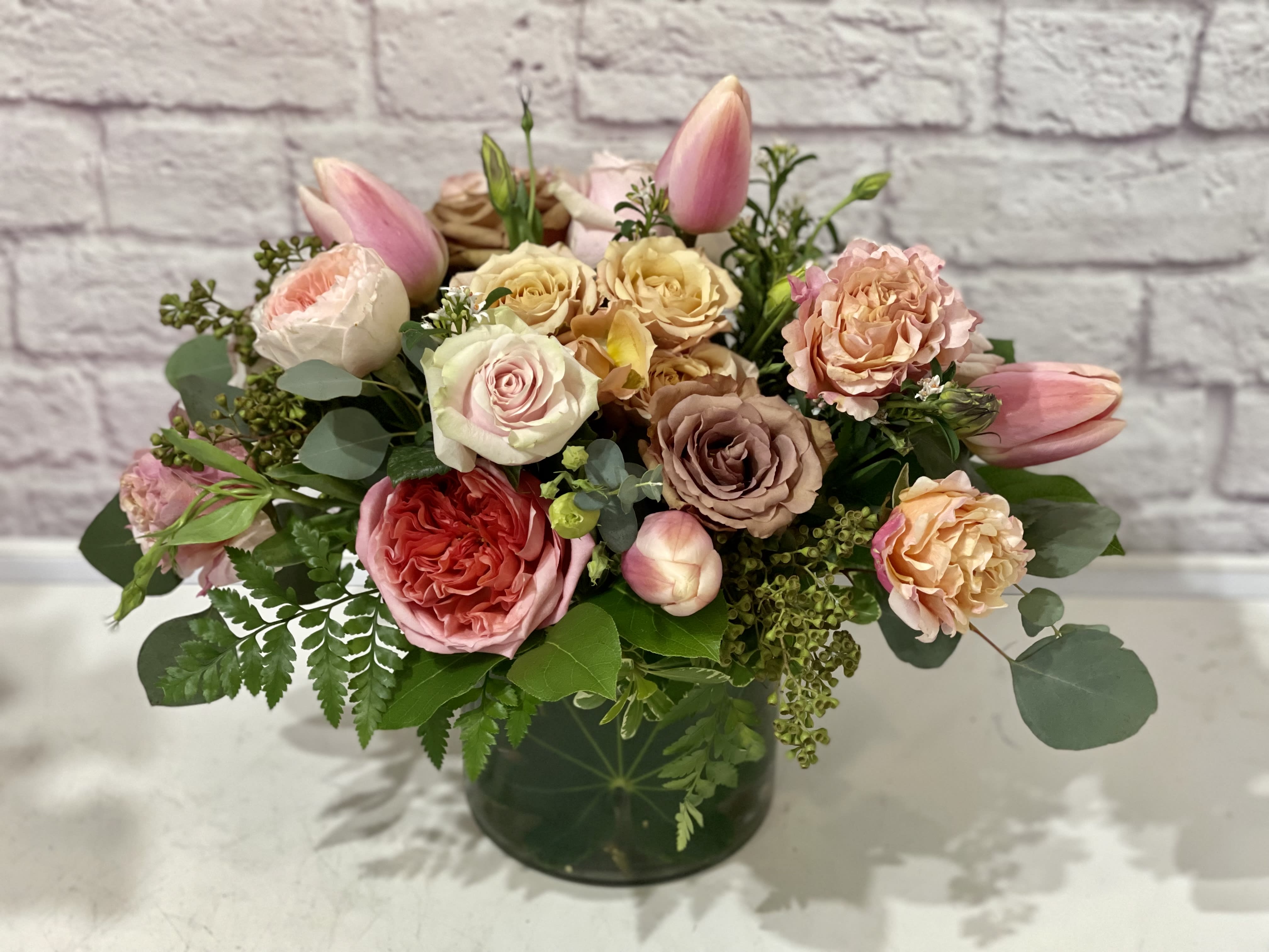 Springtime Grace - A lovely balance of blooms and high end foliage arranged in a loose, wind swept style and delivered inside a quality ceramic vase. Includes specialty “amnesia” roses, black callas, panda anemones, chocolate cosmos, chocolate Queen Anne’s lace, and blue thistle. A true winter beauty. 