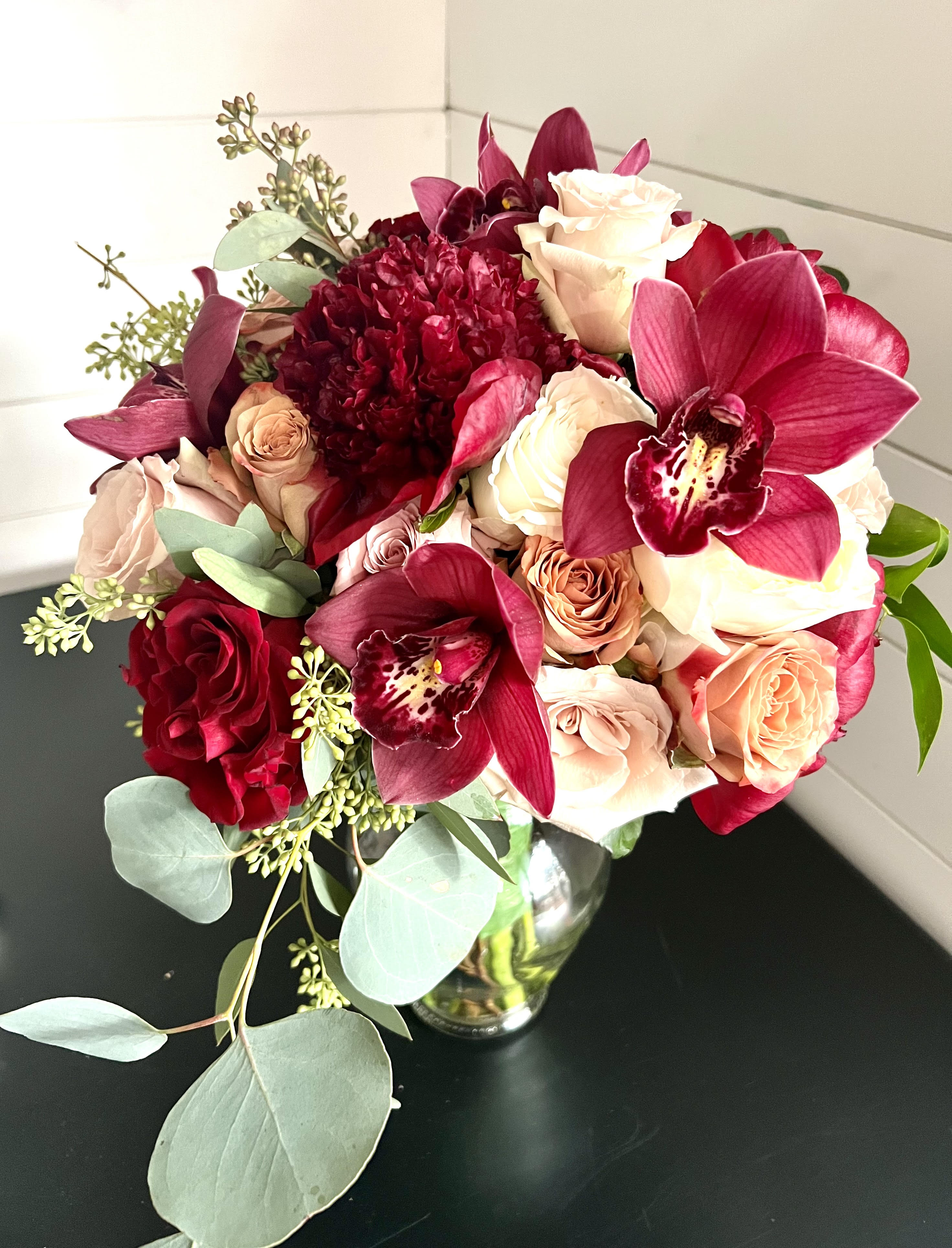 Orchids, peonies, and Roses Deluxe Bouquet - Premium bouquet filled with peonies, cymbidium orchids, white cloud roses, cappucino roses, quicksand roses, seeded and sylver dollar eucalyptus, hand tied with champagne colored double faced satin ribbon and stems accented with pearl pins.