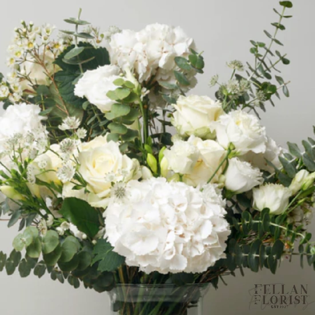Edinborough Edinborough - Delicious Proud Roses, Potent Sweet Hyacinth, Feisty Dahlia, Bold Dutch Hydrangea, Sassy Spray Roses and a touch of Creamy Green Garden Spray Roses all bundled in a Glass Vase wrapped with Vibrant Green Lily Grass.
