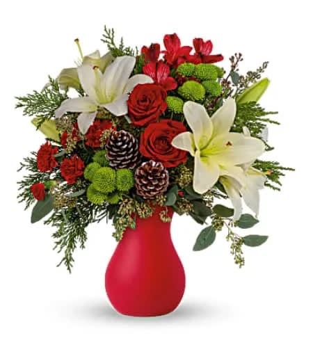 Teleflora's Yuletide Greetings Bouquet - If you're going to a holiday party, thank your hostess or host ahead of time by sending this enchanting bouquet in a timeless matte red vase. You'll be assured of a warm welcome! Red roses and carnations, green button chrysanthemums and white lilies pop against a background of lush winter greens. Orientation: All-Around