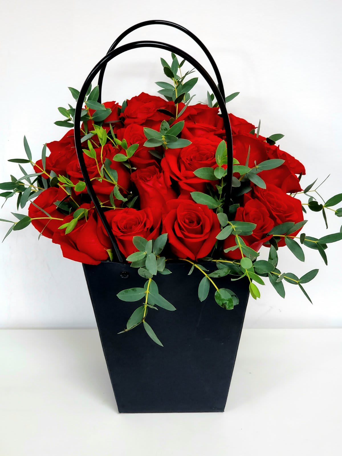 Red Roses in a Bag - Looking for eco-friendly arrangement?  Look no further.  The Red Roses in a Bag is perfect.  Simple yet Elegant and Luxurious made even more enchanting by the  dainty touches of parvifolia eucalyptus leaves. Want to make her proud? Send this unique bouquet any day...  20&quot;H by 15&quot;W  