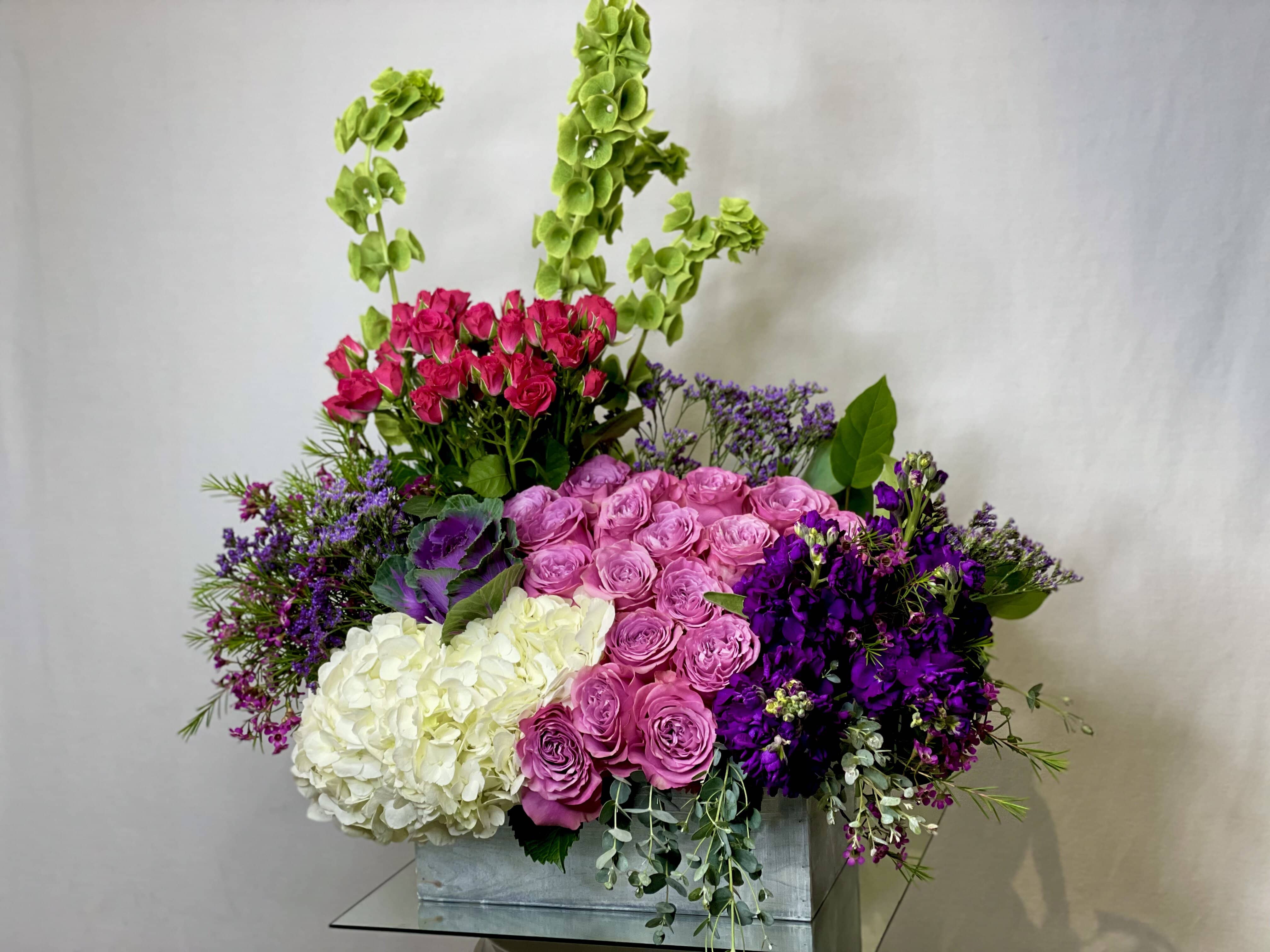 Rustic Bloom  - Beauitful Arrangement Featuring: White Hydrangeas, Red Spray Roses, Kale, Purple Stock, Eucalyptus Sliver Dollar and Purple Filler arrange in a Rustic Box.