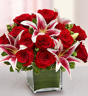 Modern Embrace Red Rose and Lily Cube - Product ID: 90973   She's always looking for the latest styles and hottest fashion trends. Send this truly original, contemporary bouquet of gorgeous red roses and elegant lilies, hand-arranged in a stylish glass cube vase, and she'll think it's the perfect accessory for her modern sensibility. Hand-crafted arrangement of romantic roses and lilies, accented by variegated pittosporum Designed by our expert florists in a modern clear glass cube vase wrapped with an exotic ti leaf; vase measures 5&quot;H Large arrangement measures approximately 14&quot;H x 14&quot;L Medium arrangement measures approximately 12&quot;H x 12&quot;L Small arrangement measures approximately 10&quot;H x 10&quot;L Our florists hand-design each arrangement, so colors, varieties, and container may vary due to local availability Lilies may arrive in bud form and will open to full beauty over the next 2-3 days
