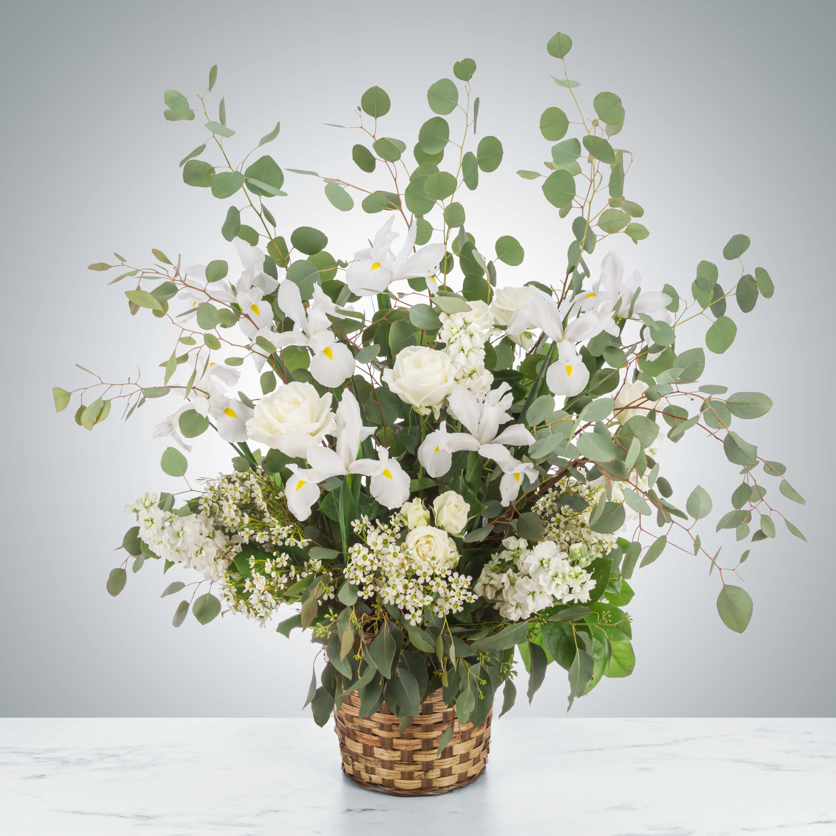 Bright Star - A wispy white and green basket featuring silver dollar eucalyptus and white iris. This arrangement smells lovely and is suitable for any type of ceremony. 