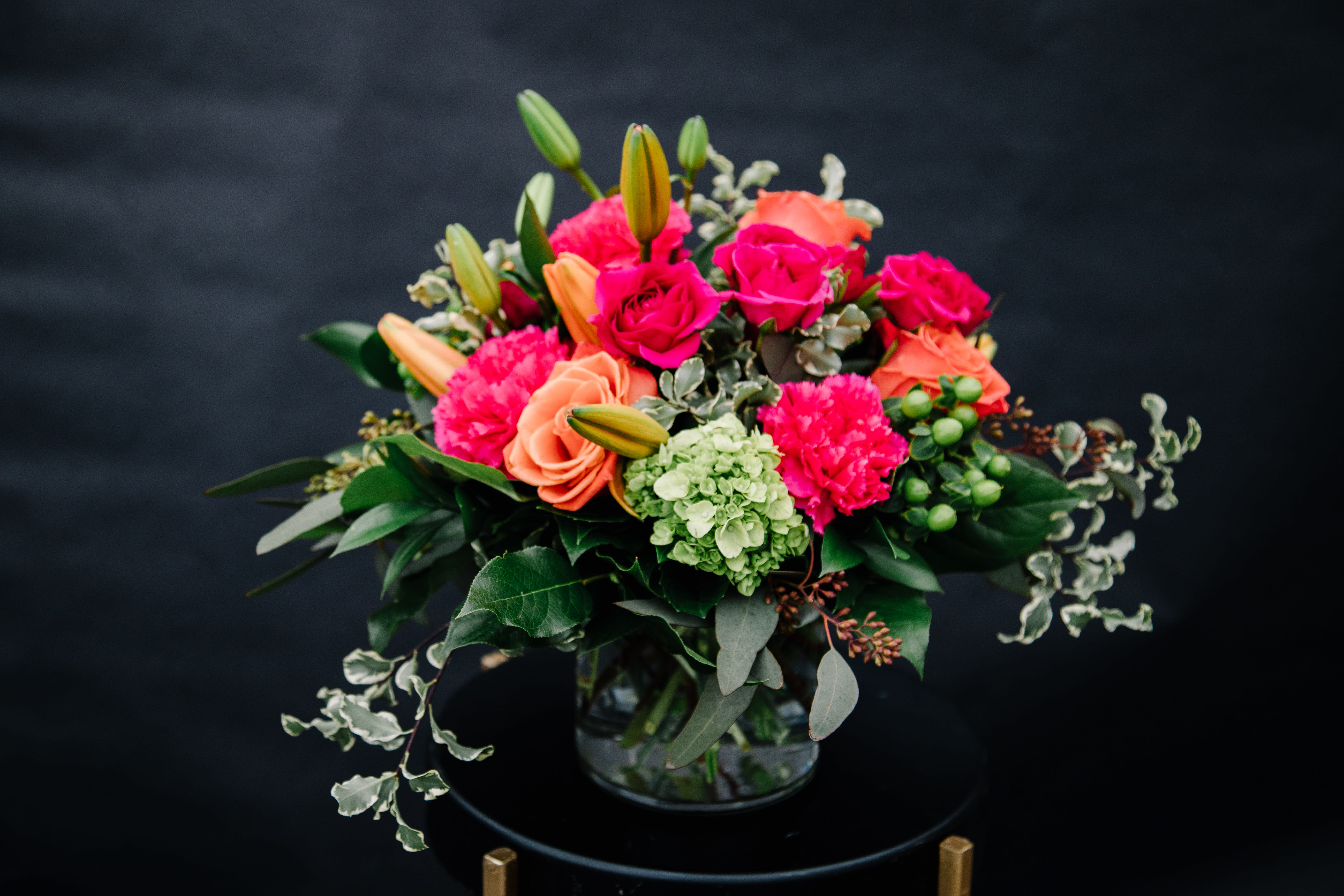 Vibrant Love - Our dazzling vibrant bouquet of love is a prefect way to celebrate a rare gem in your life.  Rich pink and orange blooms come together with bright green creating a beautiful medley of color.  Designed all around in a low modern cylinder with accents of seeded eucalyptus.