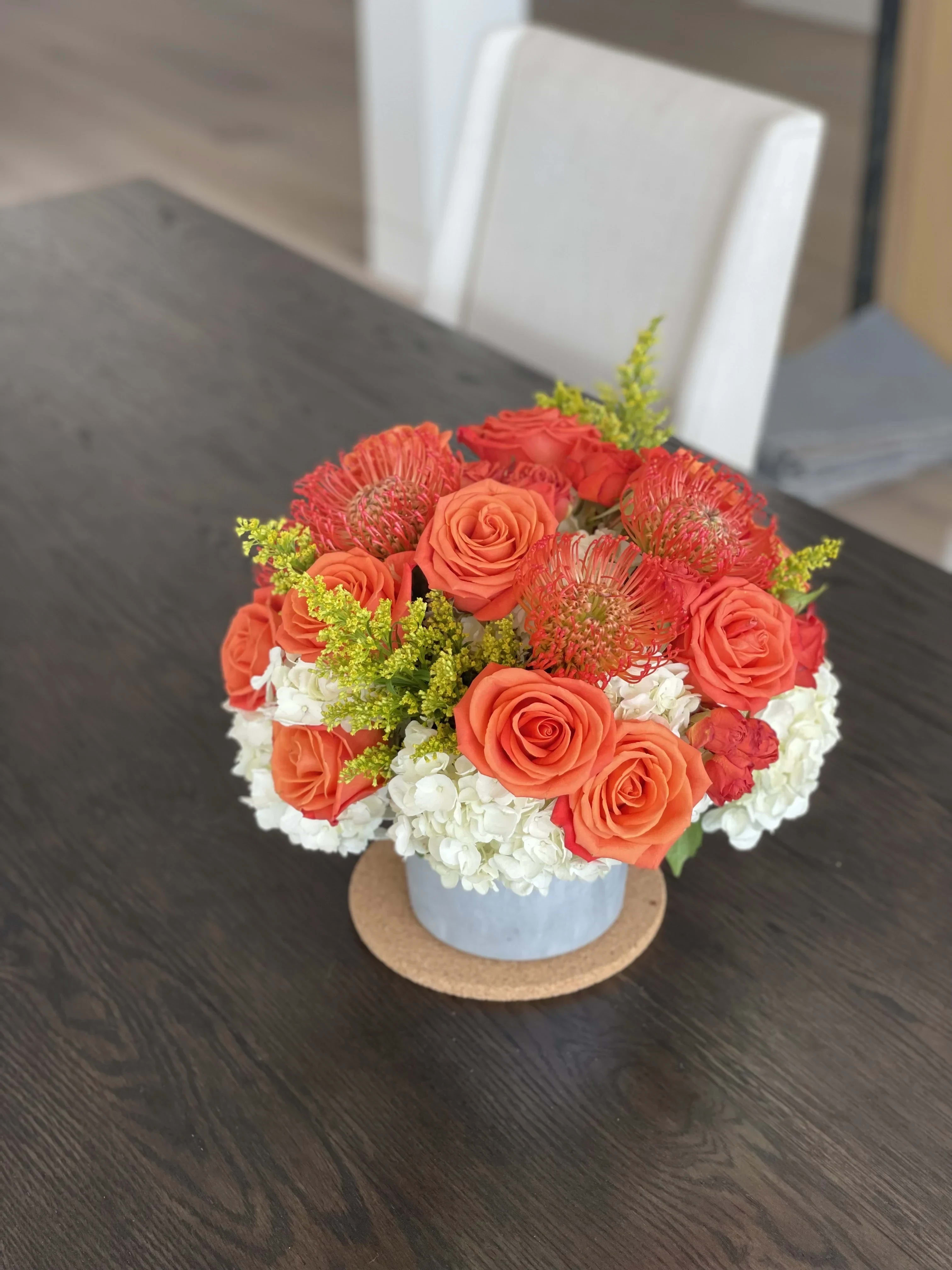 Splash of Orange - Cheerful addition to anyones space. Arrangement of Hydrangeas, Roses, Spray Roses, Greenery and Pincushions