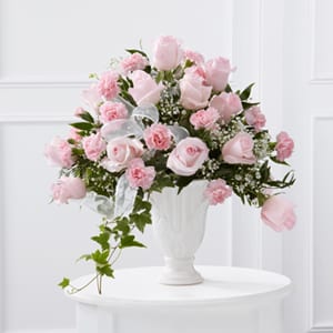 PINK ROSE SYMPATHY ARRANGMENT  NEW-S111 - Our PINK ROSE SYMPATHY ARRANGEMENT  is a presentation of elegance and grace to honor the life of the deceased.. Pale pink roses  and pink miniature carnations with lush greens and ivy all softened with a pink sheer ribbon and white baby's breath arranged in a white pedestal vase. Designed  to create a lovingly way to offer comfort and peace with each blushing bloom.