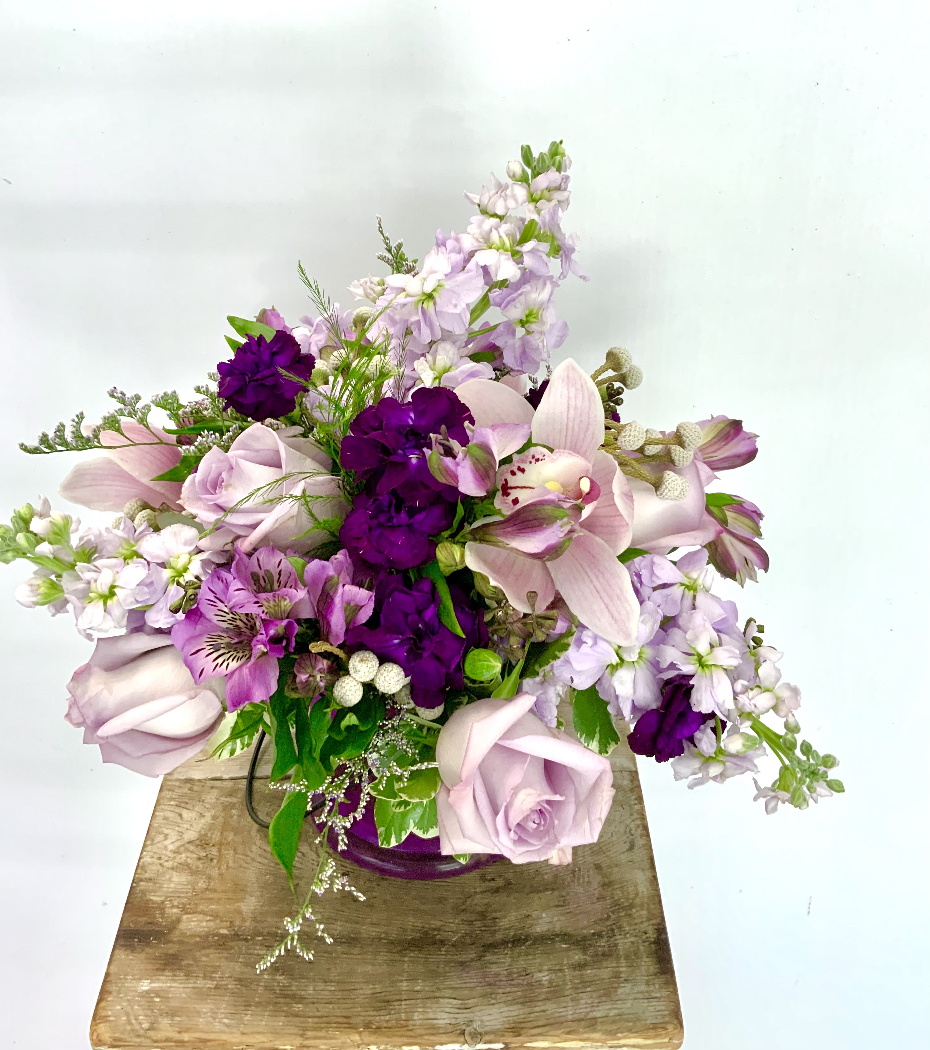Passionately Purple - Lavender roses, fragrant stock and cymbidium Orchids are the focus of this beautiful glowing gift.