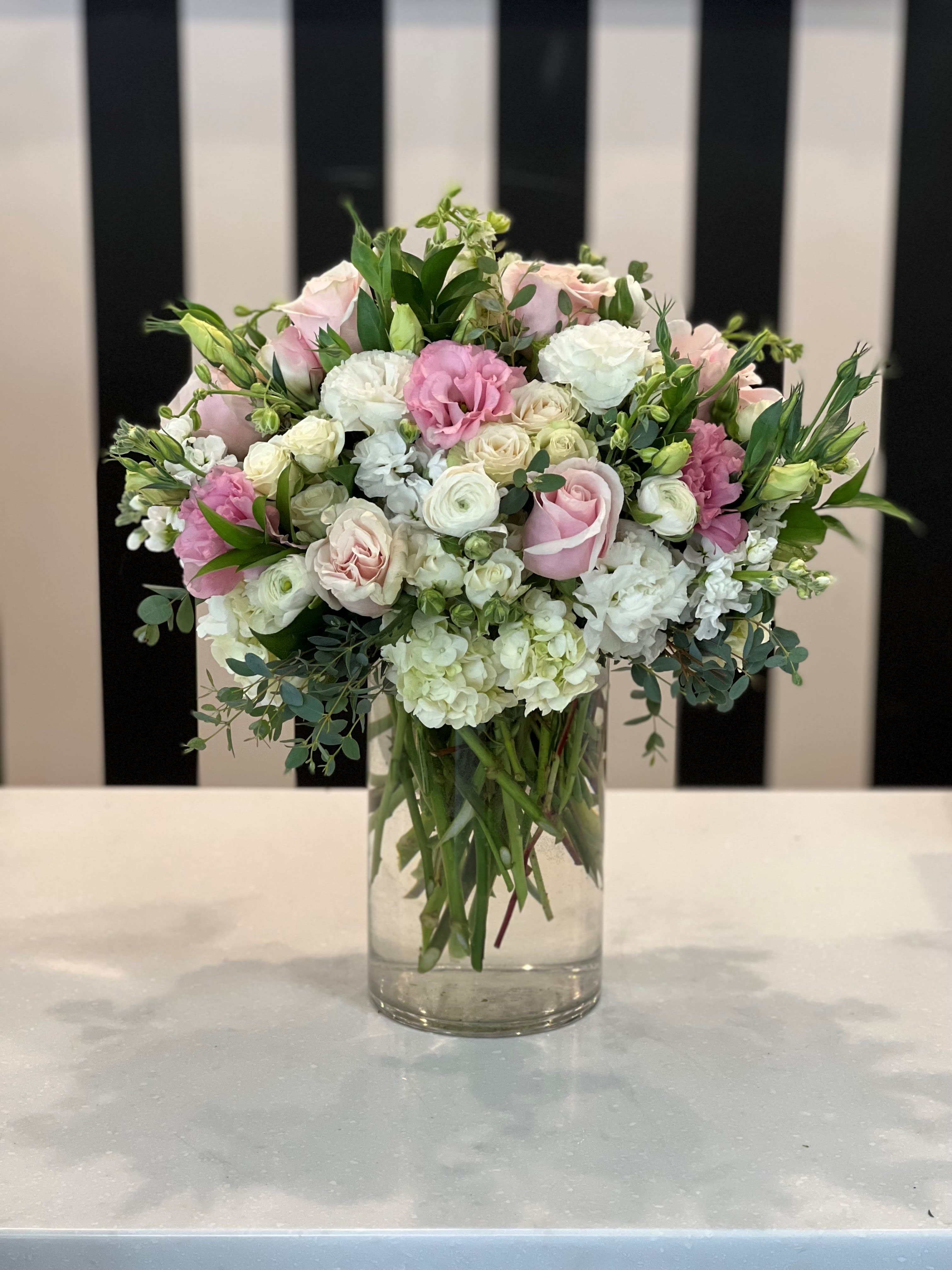 Glass Slipper  - Great for any occasion, this white crème and pink arrangement makes the perfect gift. White hydrangea, pink roses, white lisianthus and ranunculus with beautiful greenery. 