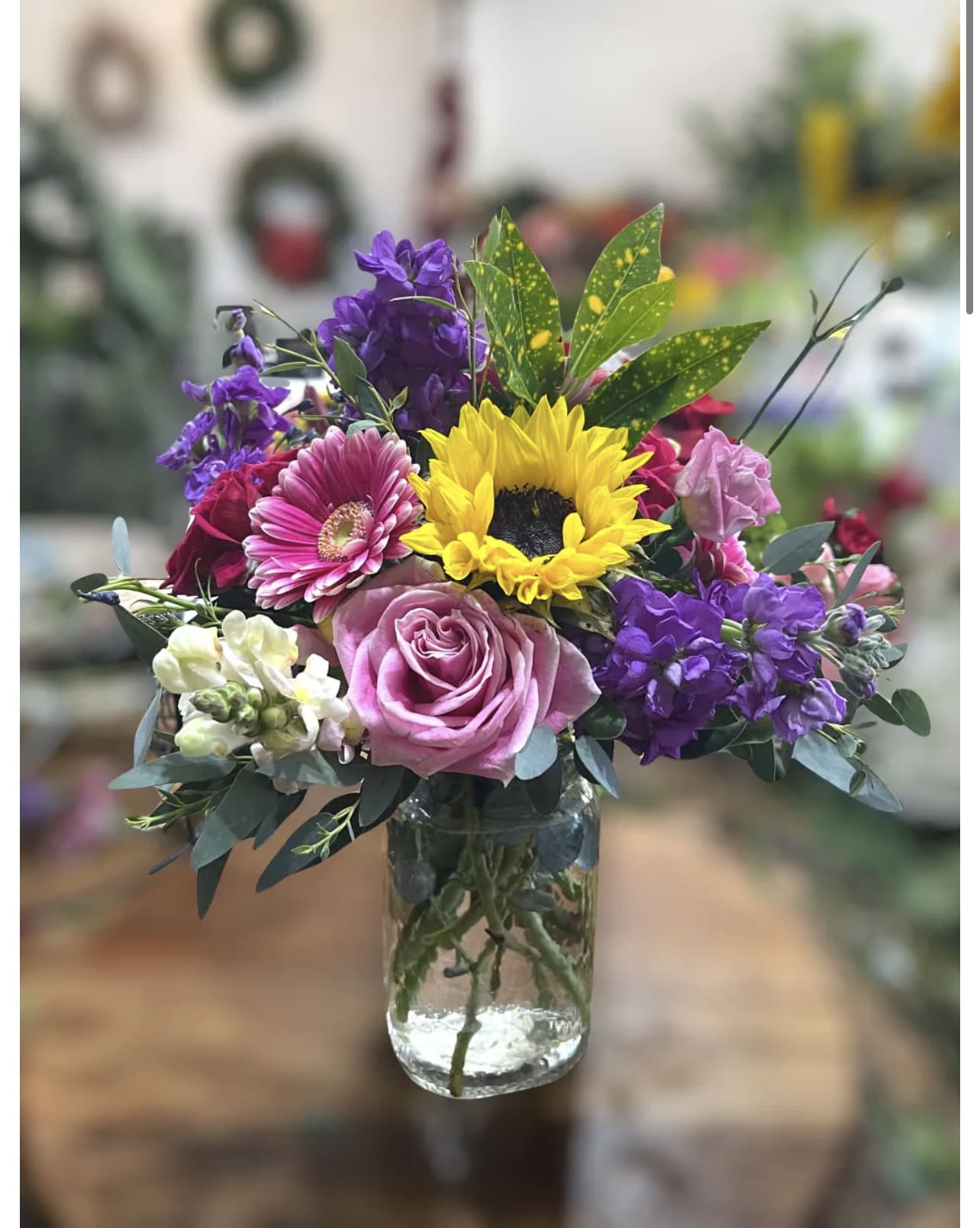 Miles of Smiles - A beautiful bouquet of blooms that evokes a big smile! This arrangement  features sunflowers, roses, Gerbera Daisies and is arranged in a glass vase. 