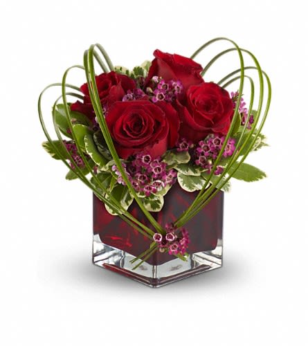 Teleflora's Sweet Thoughts Bouquet with Red Roses - If you'd like someone to think sweet thoughts about you send them this delightful bouquet! A graceful heart of bear grass is tied with purple waxflower and appears to float above red roses nestled in a ruby-red glass vase. How sweet it is! Red roses and purple waxflower accented with variegated pittosporum and bear grass arrive in a Teleflora red glass cube vase. Approximately 7&quot; (W) x 10&quot; (H) Orientation: All-Around As Shown : TFWEB114