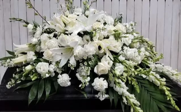 White Lily and White Rose Tribute White Lily and White Rose Tribute - This elegant casket spray is a beautiful tribute and is available in and array color as well as the soft white and ivory tones as shown. Custom hand drawn script with a sentiment of your choosing available on request to accompany this design.