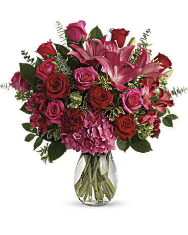 Love Struck Bouquet - A mixture of pink and red roses, pink lilies, red or pink alstromeria with fragrant greenery and lush hydrangeas. Arranged in a raspberry pink glass vase. (vase style varies by availability)  