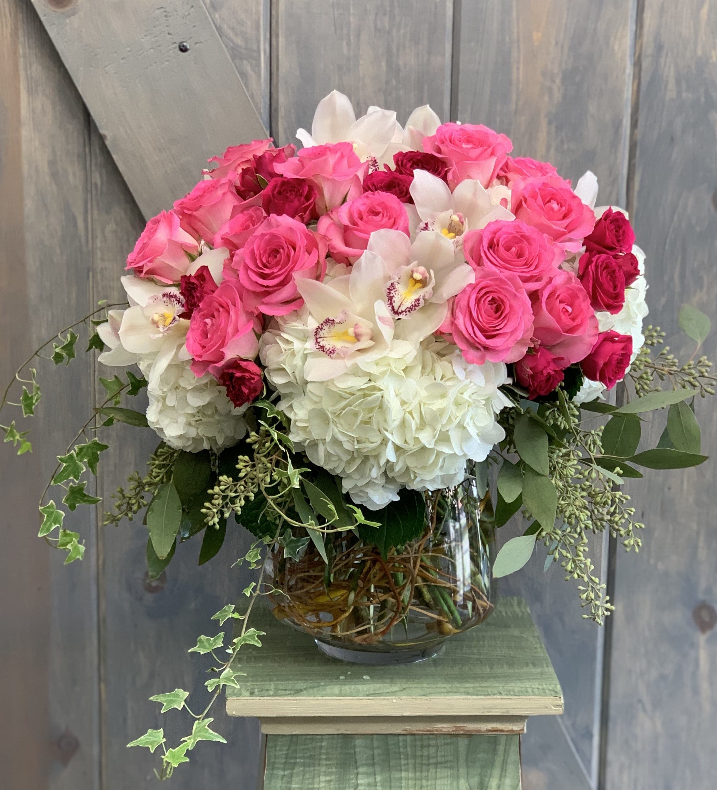 Lush - This paved masterpiece is sure to impress any recipient. The flowers included in this arrangement are Roses, Spray roses, Hydrangea, Cymbidium Orchids, Seeded Eucalyptus, and Ivy