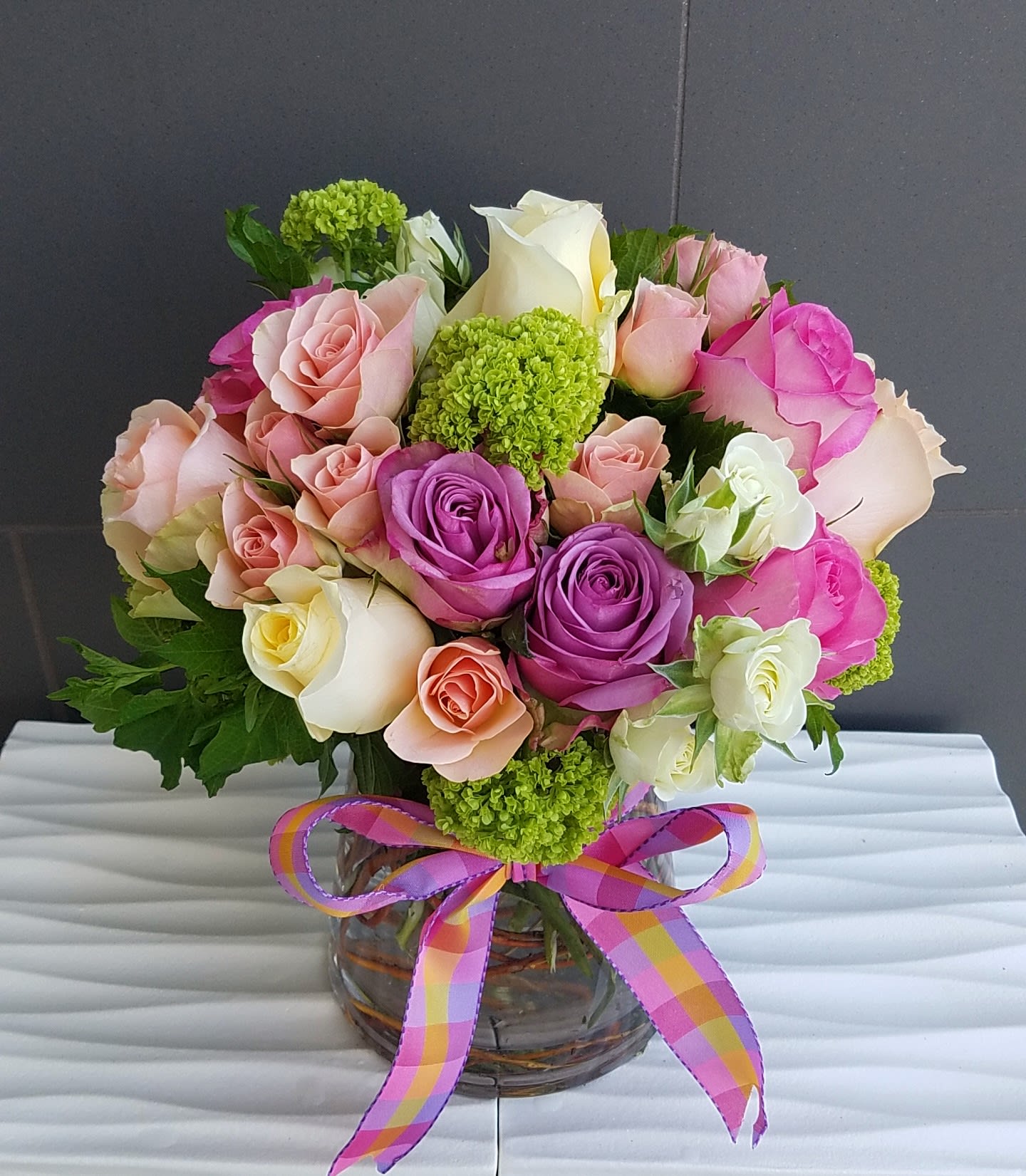 Pastel Delight - This arrangement was designed in a compact style with a mix of  pastel colored roses, spray roses, and green viburnum. 