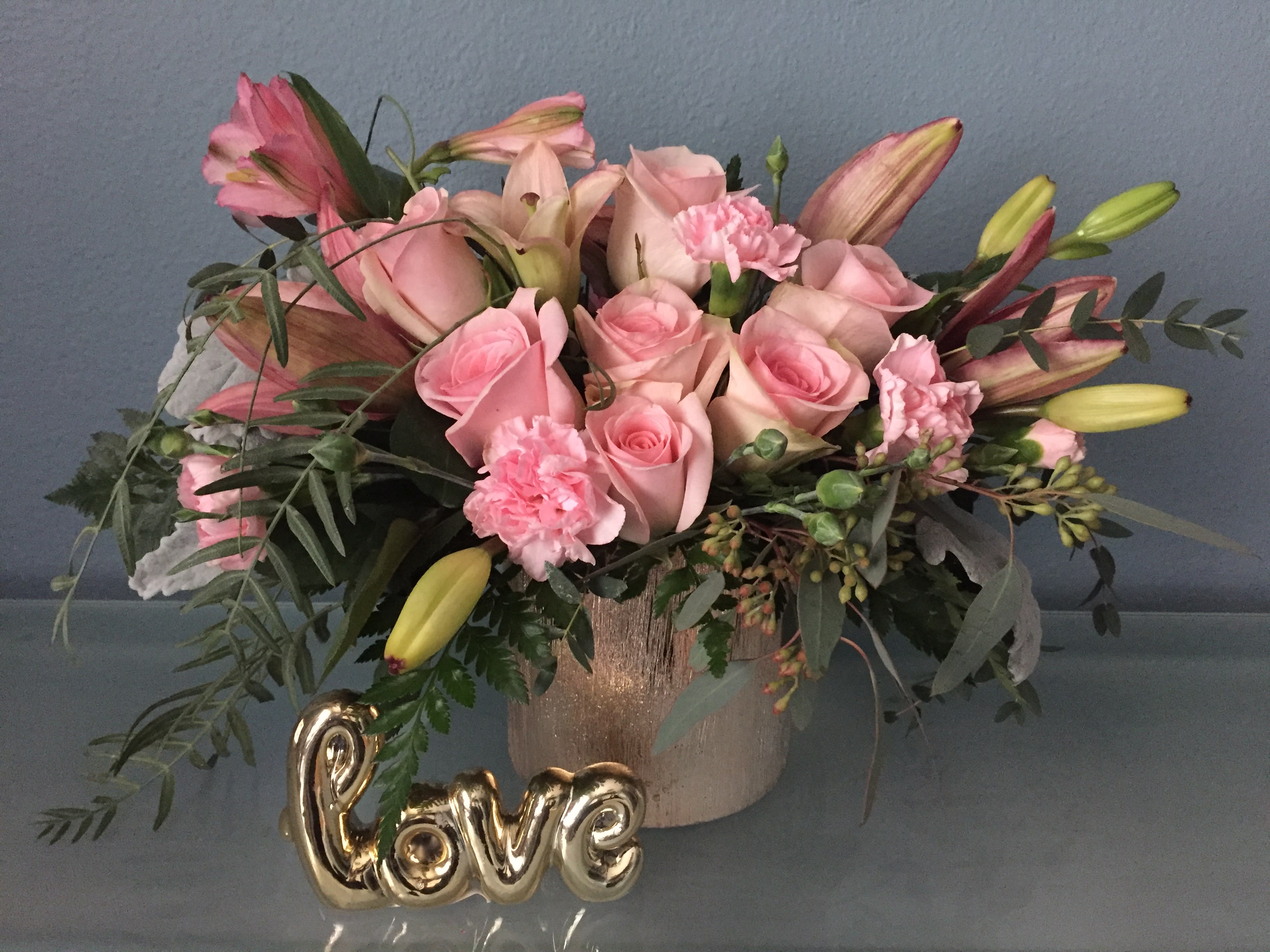 Fabulous Flora  - Just fabulous! From its perky rose color gold cube and perfect pink roses, to its textural greens and dramatic pink lilies, this chic bouquet is flora at its finest!  •This gorgeous bouquet features pink roses, pink asiatic lilies, pink alstroemeria, pink miniature carnations, dusty miller, parvifolia eucalyptus, and seeded eucalyptus.  •Delivered in Rose Color Gold Cube. •Orientation: All-Around 