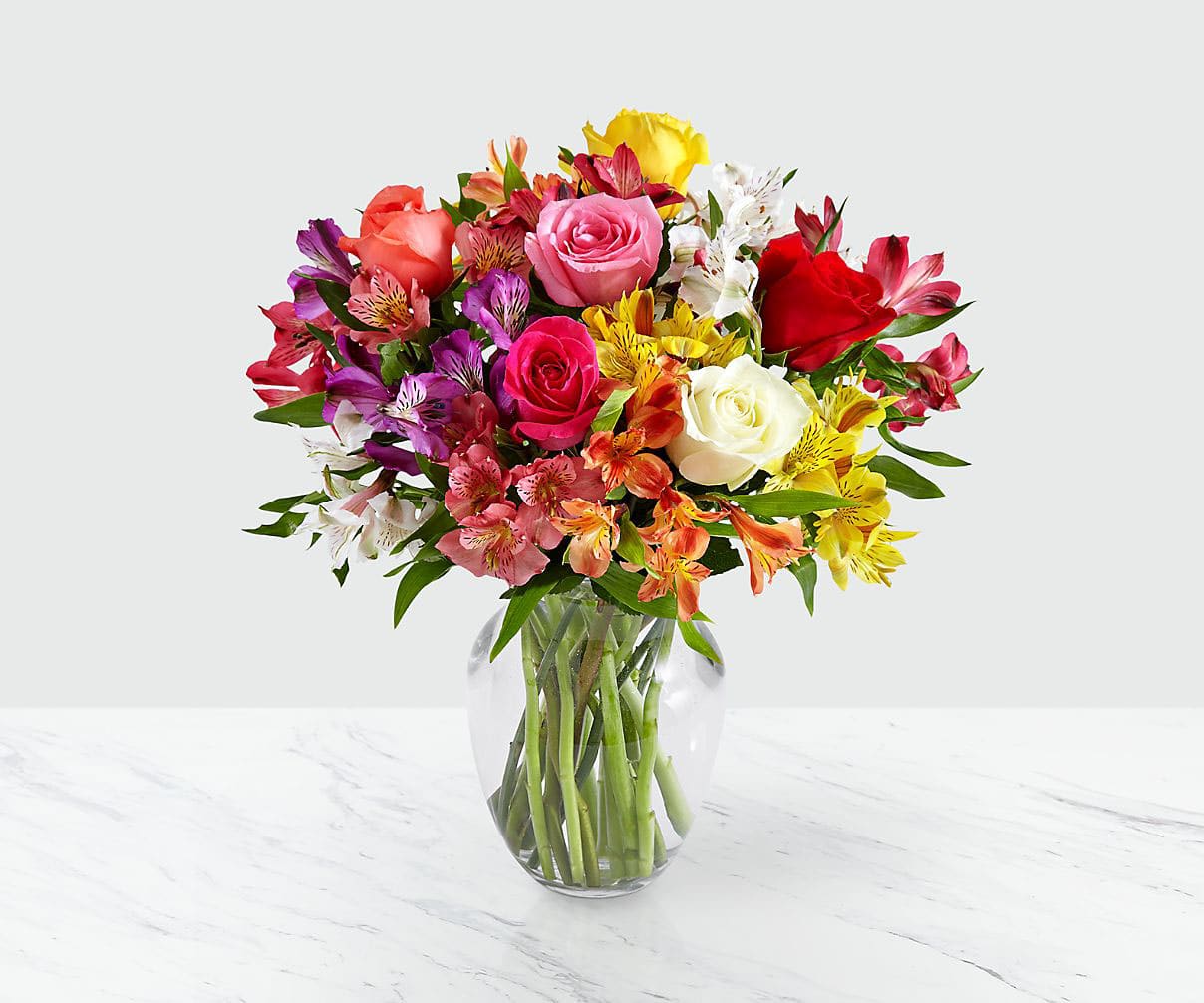 Smiles &amp; Sunshine with Glass Ginger Vase - Send a sunny splash of color and brighten their day with this vibrant bouquet of 10 Peruvian lilies, mixed with 6 multi-colored roses. Symbolic of friendship and devotion, each stem of Peruvian lily has multiple blooms and is sure to warm their heart.