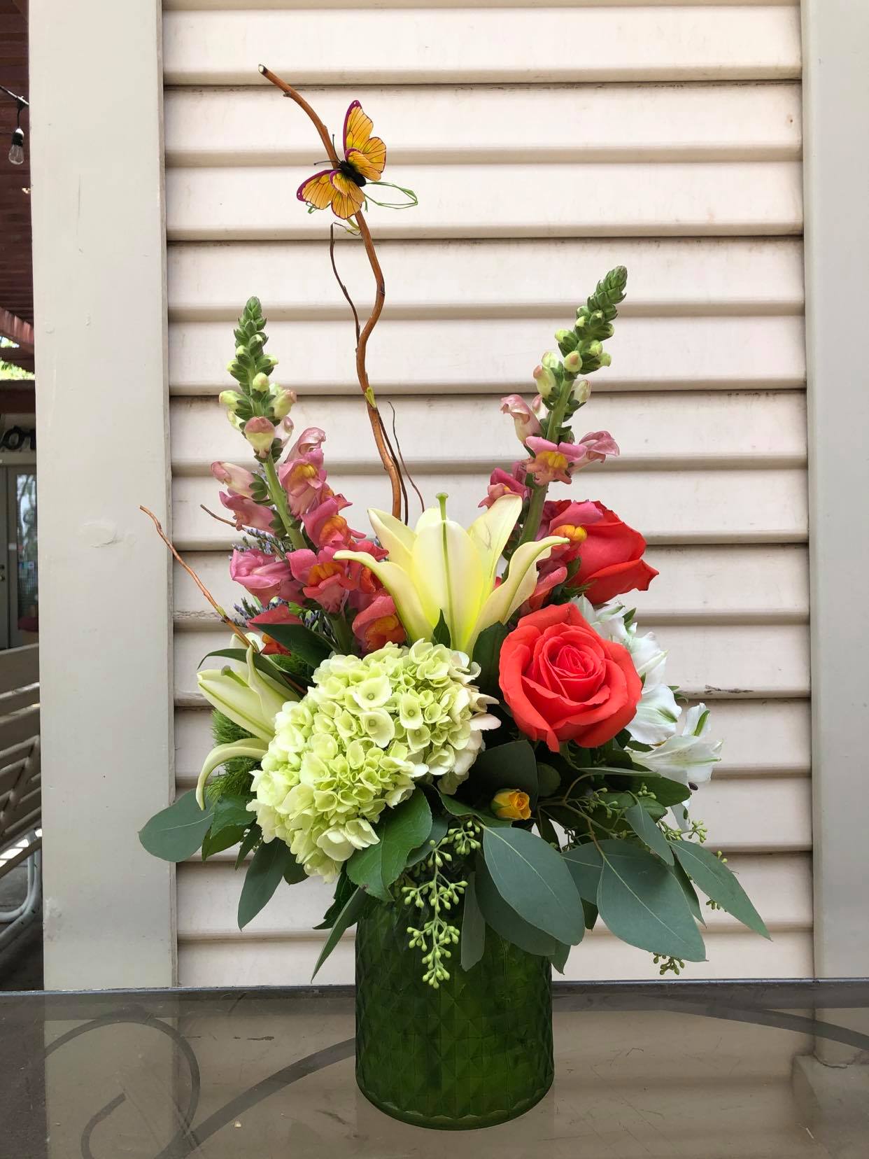 The Waverly - Snap dragons, roses, mini green hydrangea, alstroemeria and lilies with curly willow accents and a butterfly 