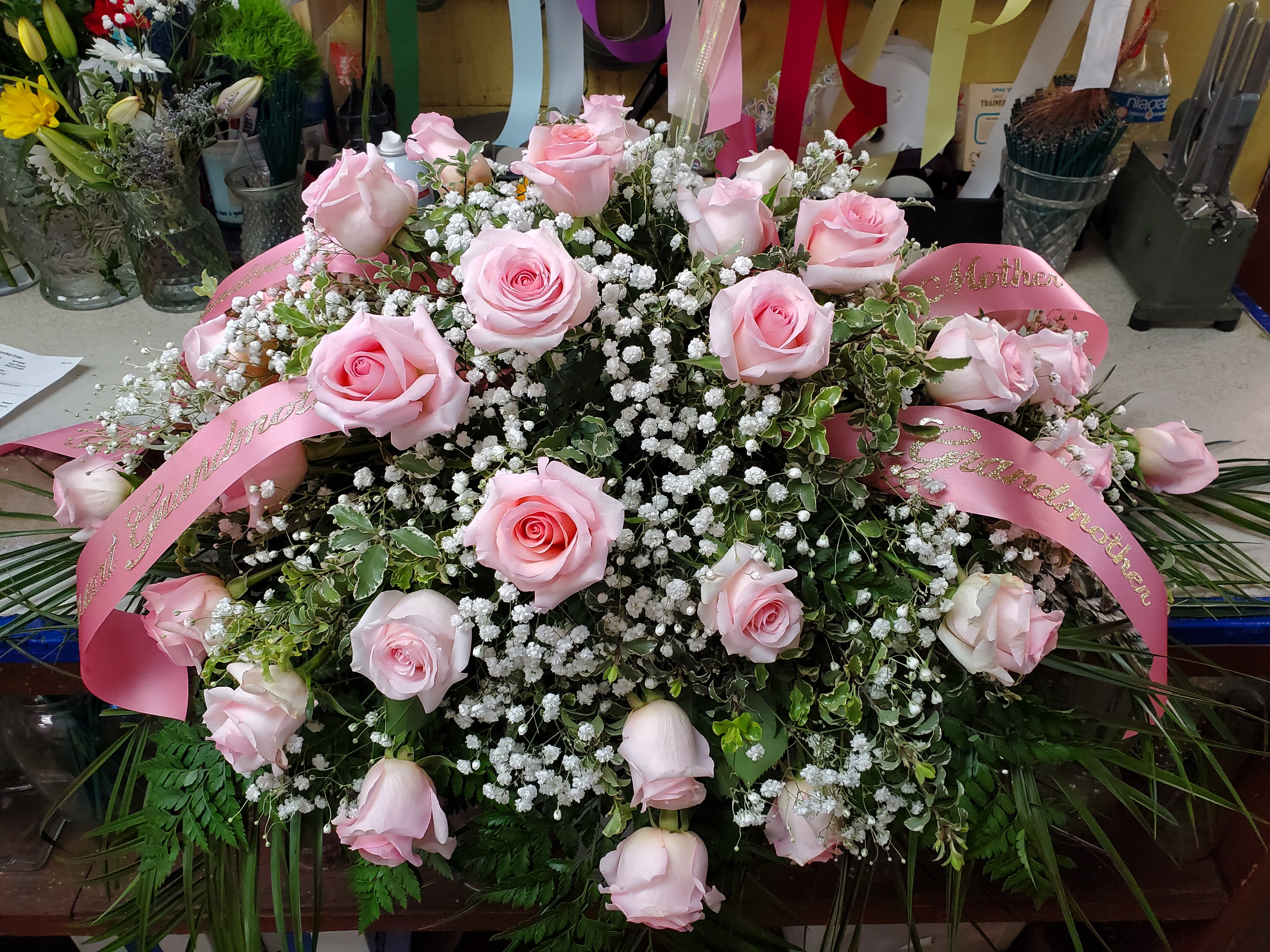 Simply Sweet Casket Spray - This spray comes with Roses, Baby's breath and greens. Design with your own color choice on the roses.  125.00-175.00