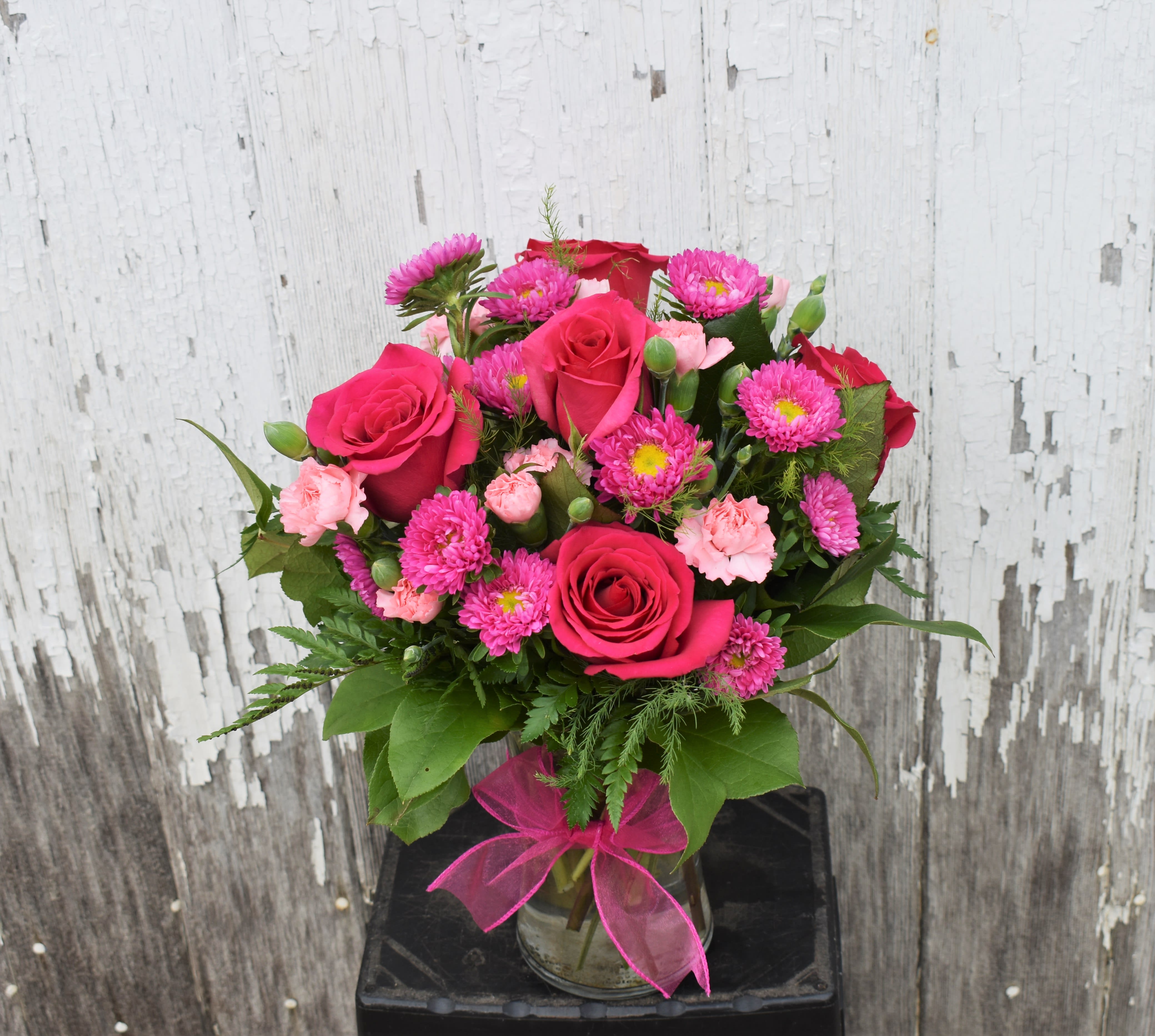 Precious Heart Bouquet - This bouquet is a blushing display of loving kindness. Fuchsia roses are sweetly stunning amongst pink matsumoto asters, pink mini carnations and lush greens. Arranged in a classic clear glass vase, this bouquet boasts pink perfection to convey your warmest wishes. 