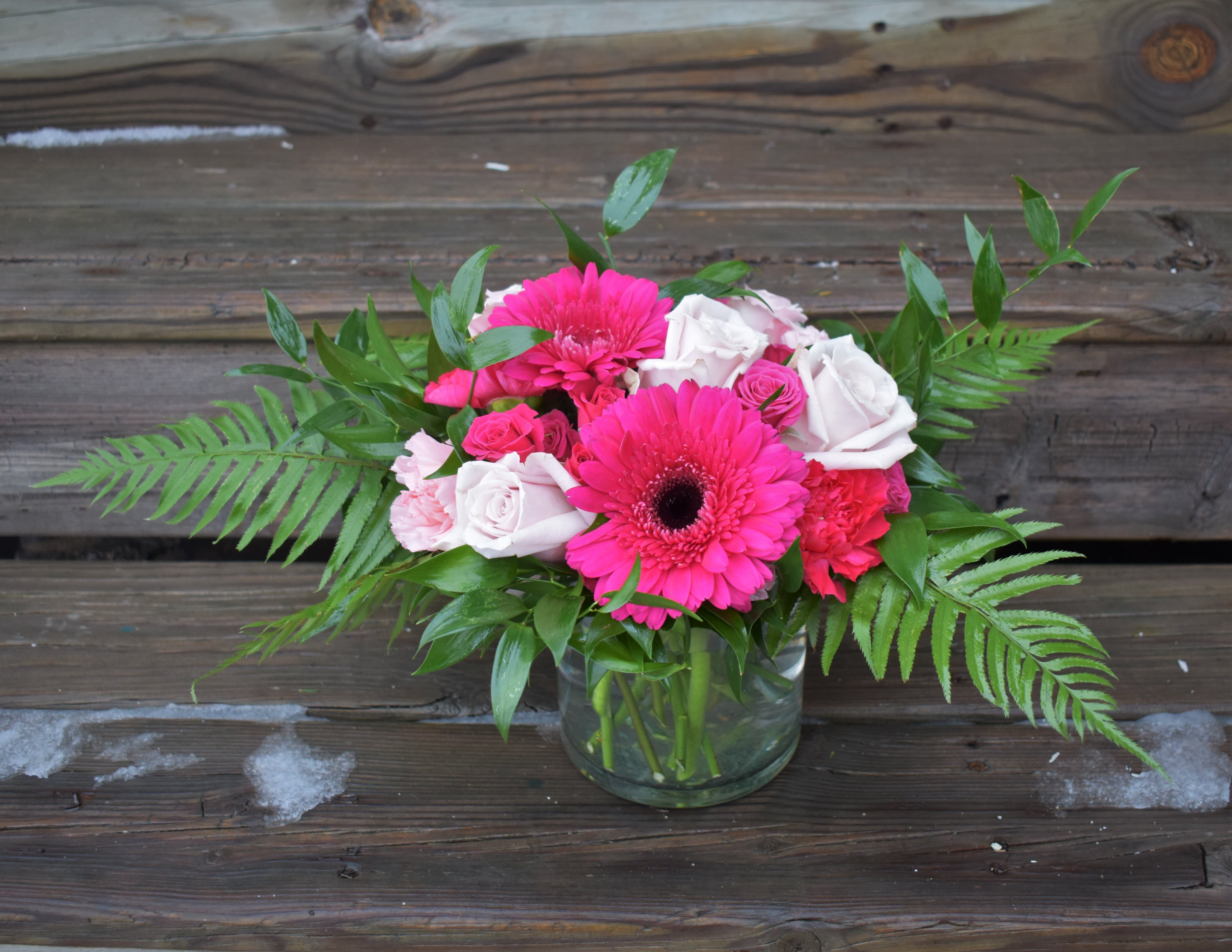 Party Girl - This vibrant bouquet showcases gerber daisies, roses, spray roses, carnations, and lush greenery and is designed in a low cylinder vase...The perfect way to celebrate a special someone! 
