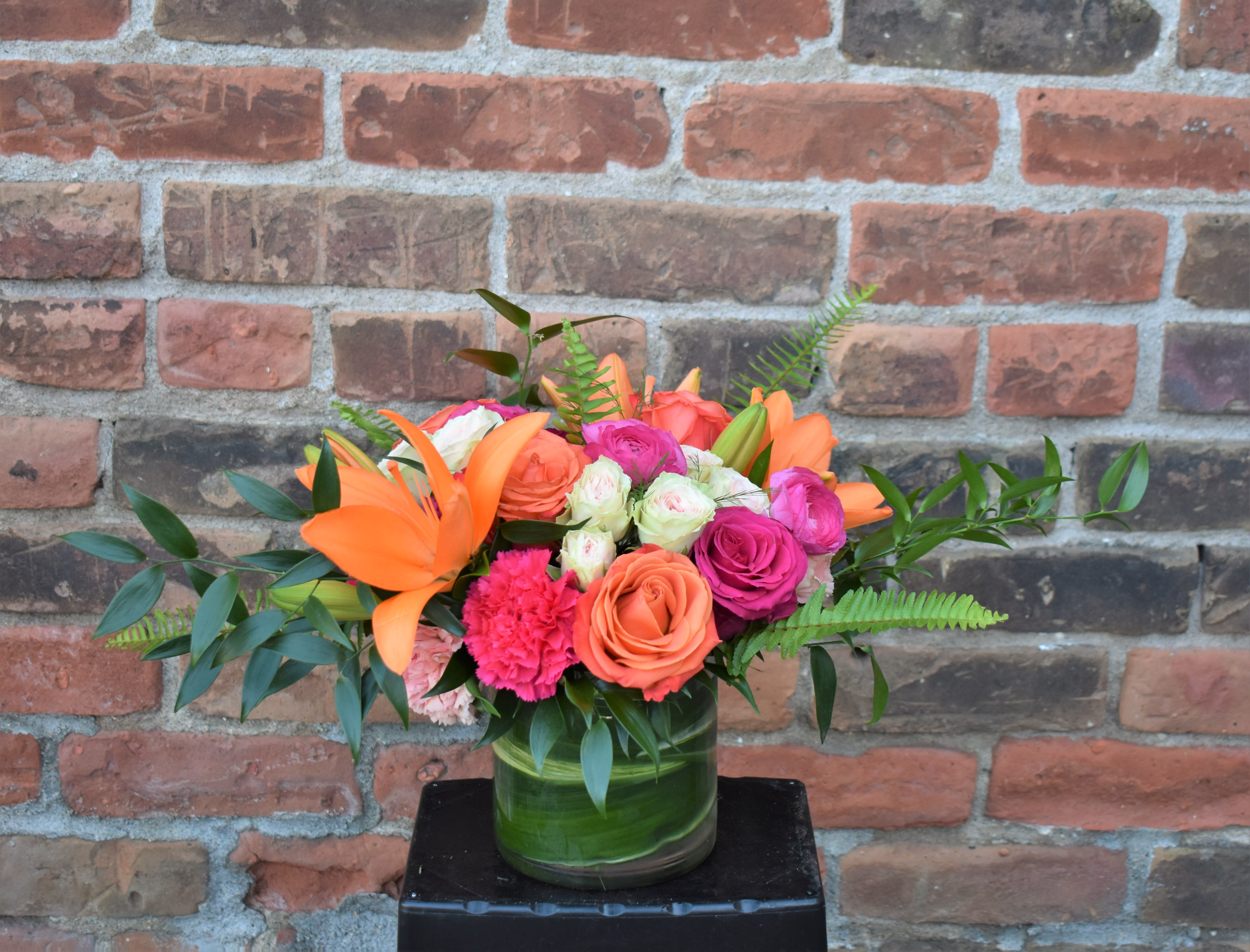 Summer Sunset - Vibrant oranges, bright pinks, and soft blushes create a celebratory bouquet! A mix of roses, lilies, and carnations accented by lush greens and ferns and are perfect for celebrating every occasion!