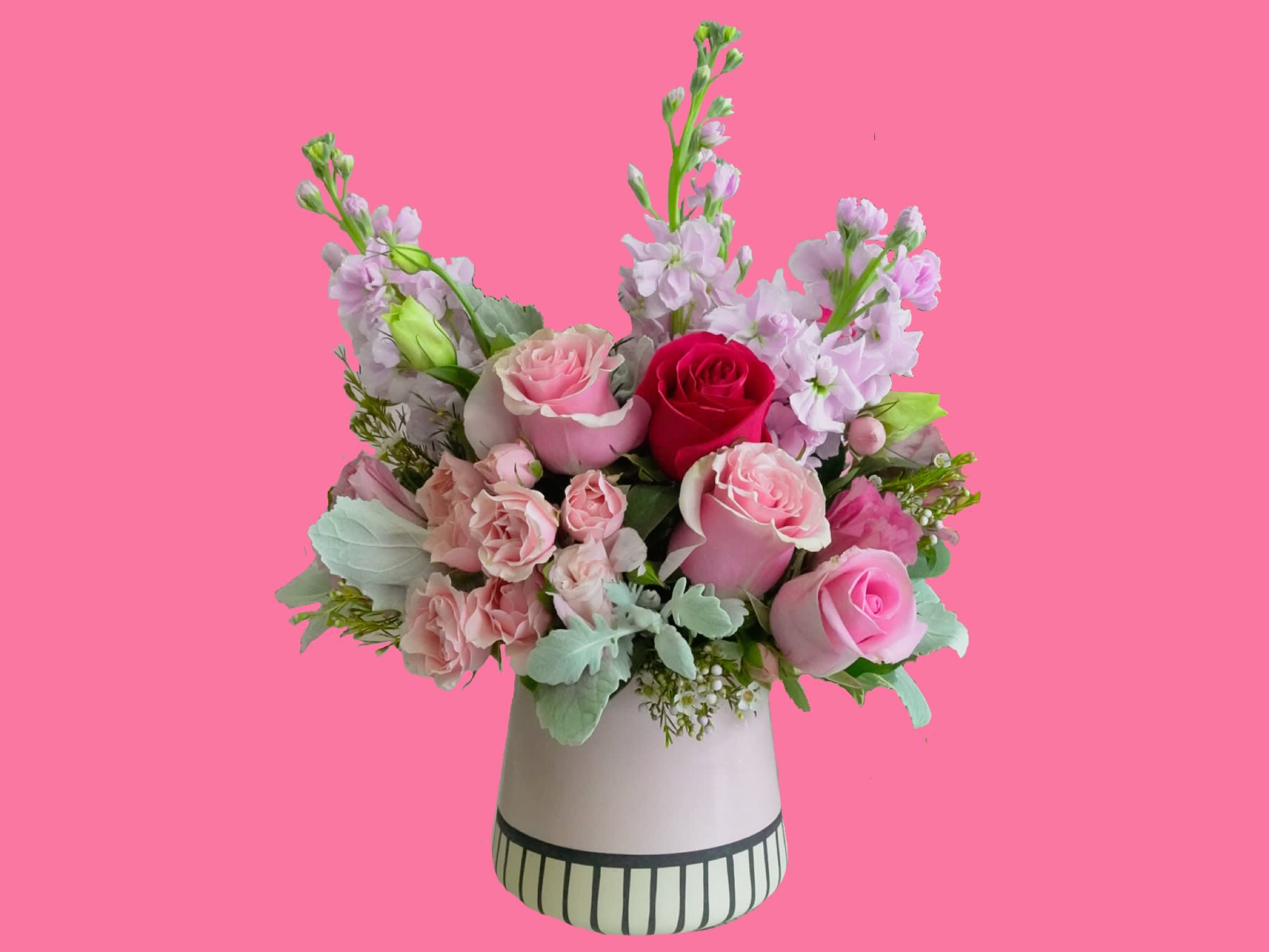 Precious Pink  - This impressive bouquet includes pink roses, hot pink roses, pink spray roses, white lisianthus , stock , dusty miller , wax with assorted greenery. Delivered in a pink vase. Orientation: All-Around