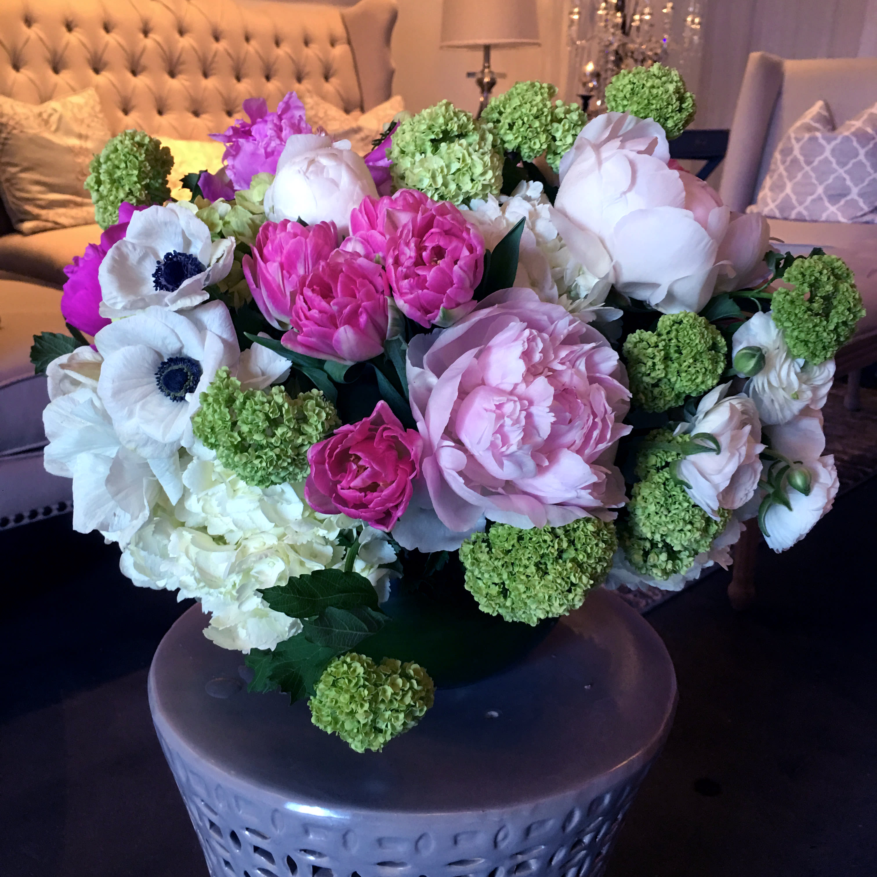 Peony Party - A traditional garden-style arrangement full of Spring's freshest and most beautiful flowers. White hydrangea, pink tulips, green viburnum, white anemones, and of course, pink peonies sit in a 10 inch leaf-lined fishbowl style glass vase. 