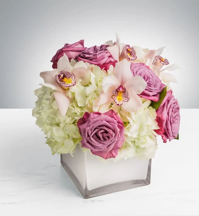 Pop of Lavender by BloomNation™ - Our most popular arrangement! Pop of Lavender by BloomNation™ is the perfect gift to wish someone a happy birthday or to say thank you.   Arrangement Details: Includes white cymbidium orchids, lavender roses, and white hydrangea.  APPROXIMATE DIMENSIONS:10&quot; H X 11&quot; W X 11&quot;L