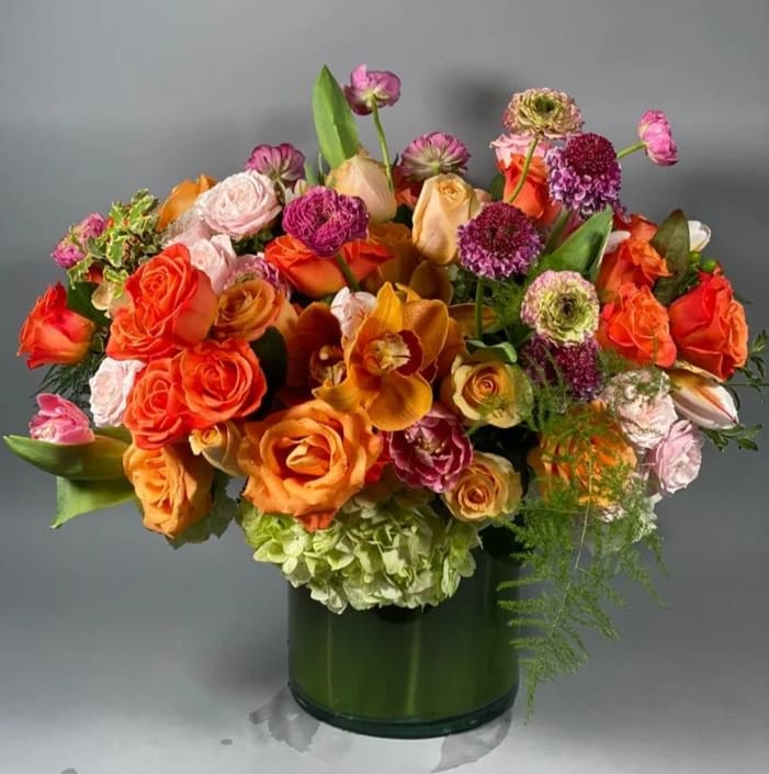 Orange U Cute - Amber, honey, salmon, carrot, salamander.... So many shades of orange come together for this delightfully cheerful arrangement full of roses, spray roses, tulips, ranunculus, cymbidium orchids, and the ever luxurious scabiosa flowers.