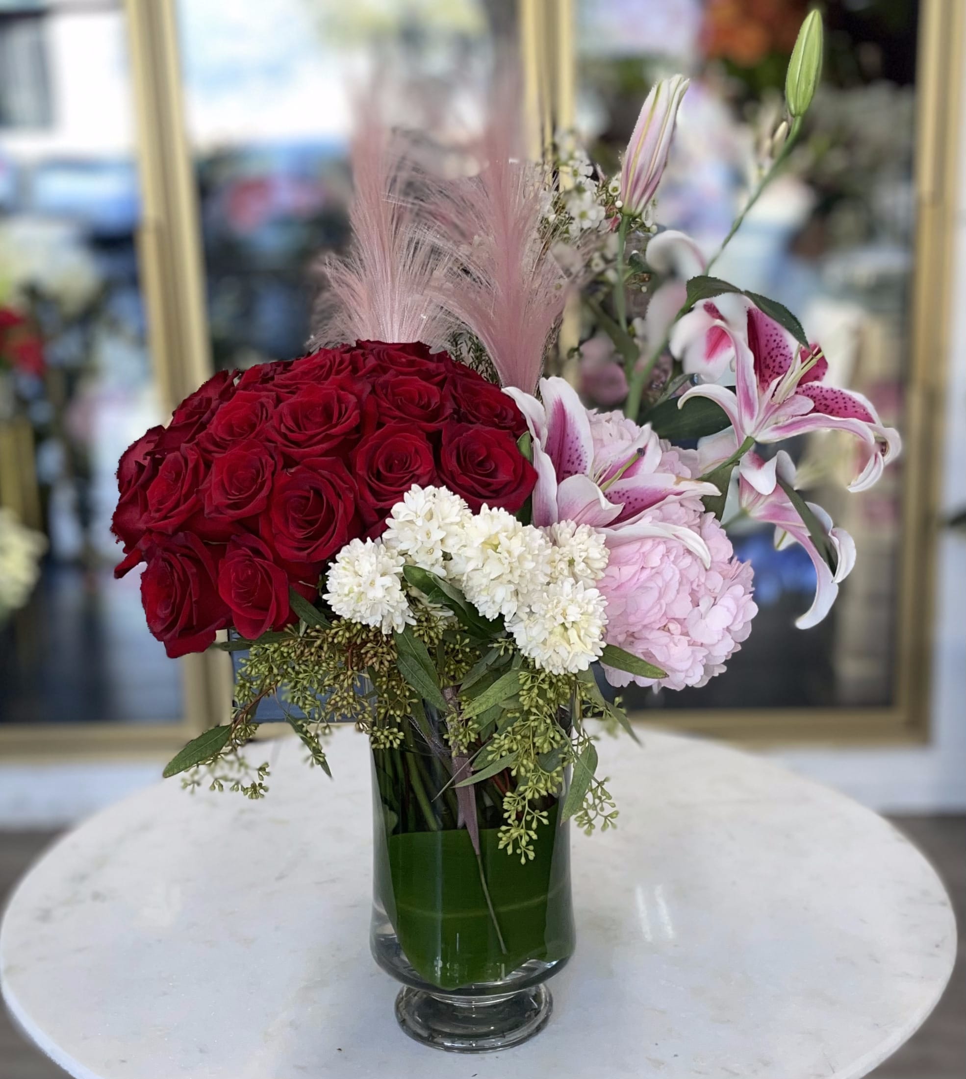 Love All Love All - Love All consists of Red Roses, Stargazer Lilies, Pink Hydrangeas, wax flowers, and assorted greens in a clear glass vase.