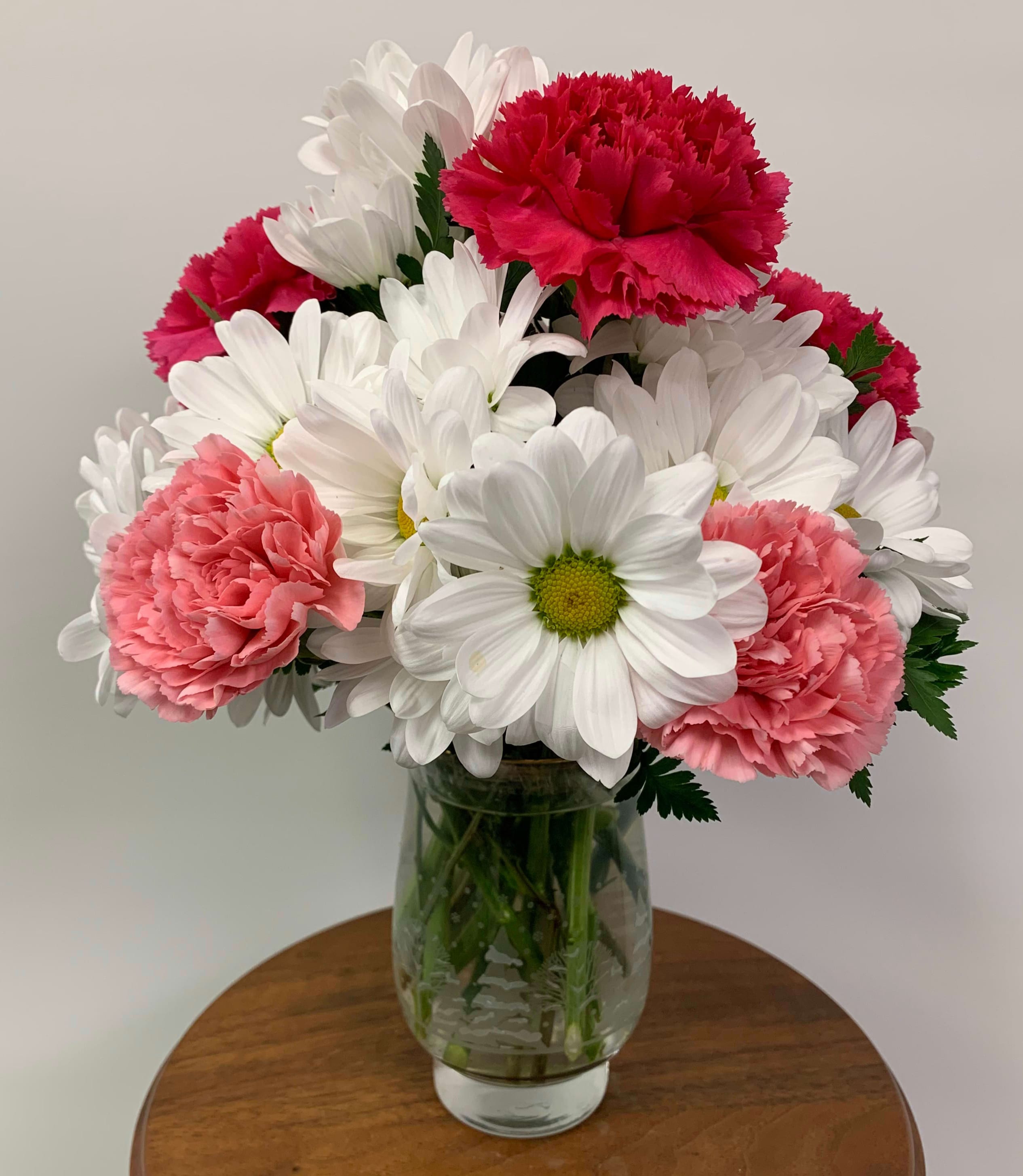 Daisy Crazy - A modest gift that will make a lasting impression. Daisy Crazy is the perfect gift for a birthday or just to show you care.  Carnation color will be choice of designer unless you specify in special instructions. Arrangement Details: Comes in a clear glass vase of designers choice and includes white chrysanthemum spray daisies, carnations, and assorted greenery.