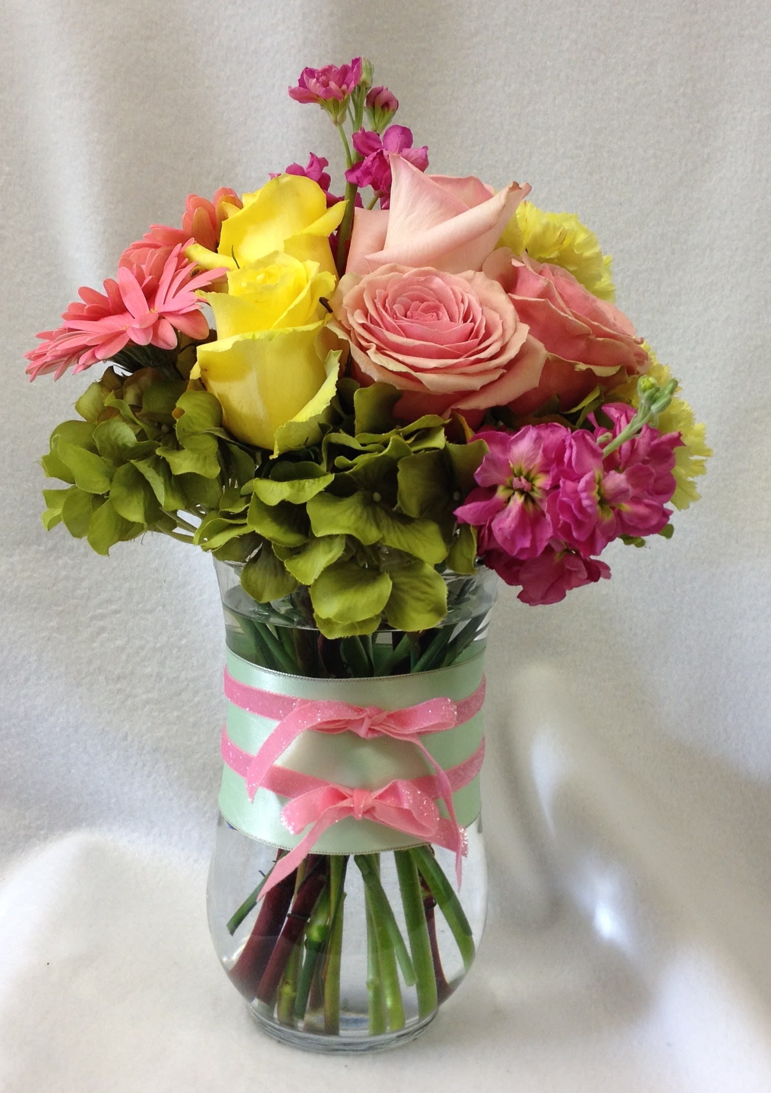 Fashionista Blossoms - This arrangement would be perfect for any girl with an eye for style. It's a must-have for fashionistas everywhere. Gorgeous hydrangea, yellow and light pink roses, gerberas, light yellow carnations and green button spray chrysanthemums are delivered in a pretty gathering vase. Not just any vase, of course, this one's accessorized with a decorative ribbon.  Flowers may vary depending on availability. Orientation: All-Around