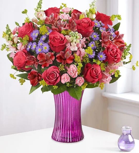 Enchanted Medley - Love is a magical feeling. Celebrate with our romantic medley of blooms, gathered inside our striking, new fluted violet gathering vase. Designed in vintage pressed glass with ribbed detailing, this is one gift that won’t leave them wondering what’s on your mind…and in your heart.