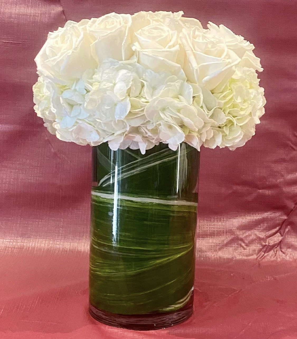 Custom arrangement of white roses &amp; white hydrangeas in leaf lined clear glass vase. - Custom arrangement of white roses &amp; white hydrangeas in leaf lined clear glass vase.