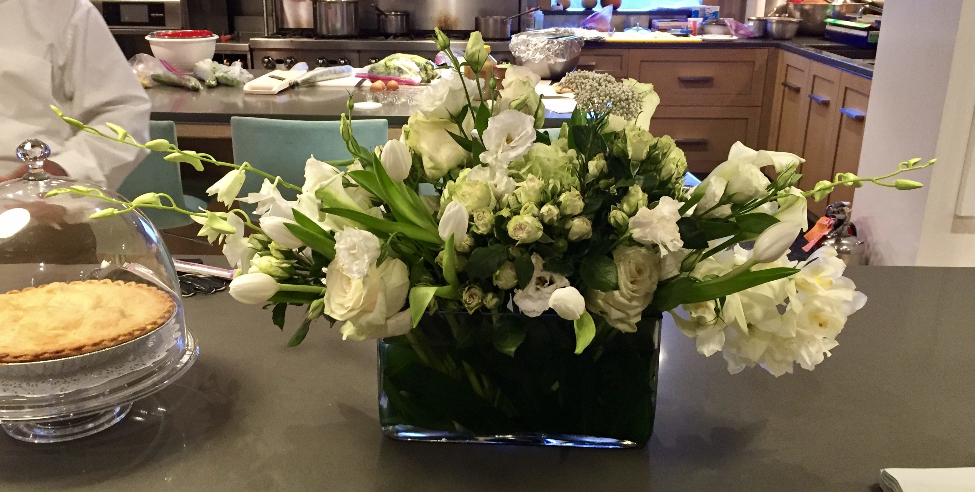 Custom arrangement of white tulips, white roses, white spray roses &amp; white lisianthus - Custom arrangement of white tulips, white roses, white spray roses, white orchids &amp; white lisianthus in clear glass container with leaf wrap.