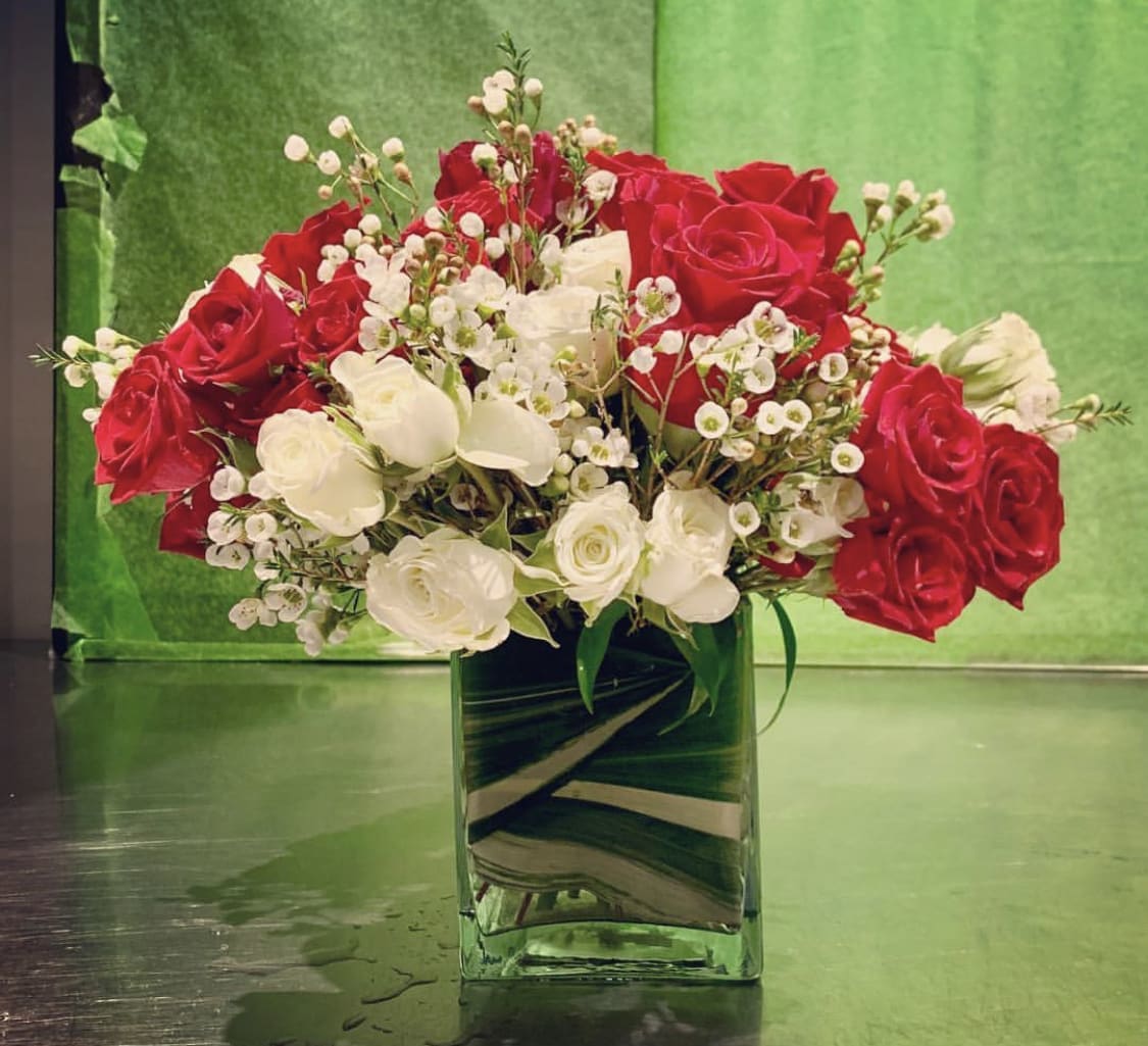 Custom arrangement of red roses, white spray roses & white wax flower Custom arrangement of red roses, white spray roses & white wax flower - Custom arrangement of red roses, white spray roses & white wax flower in clear glass cube with leaf wrap.