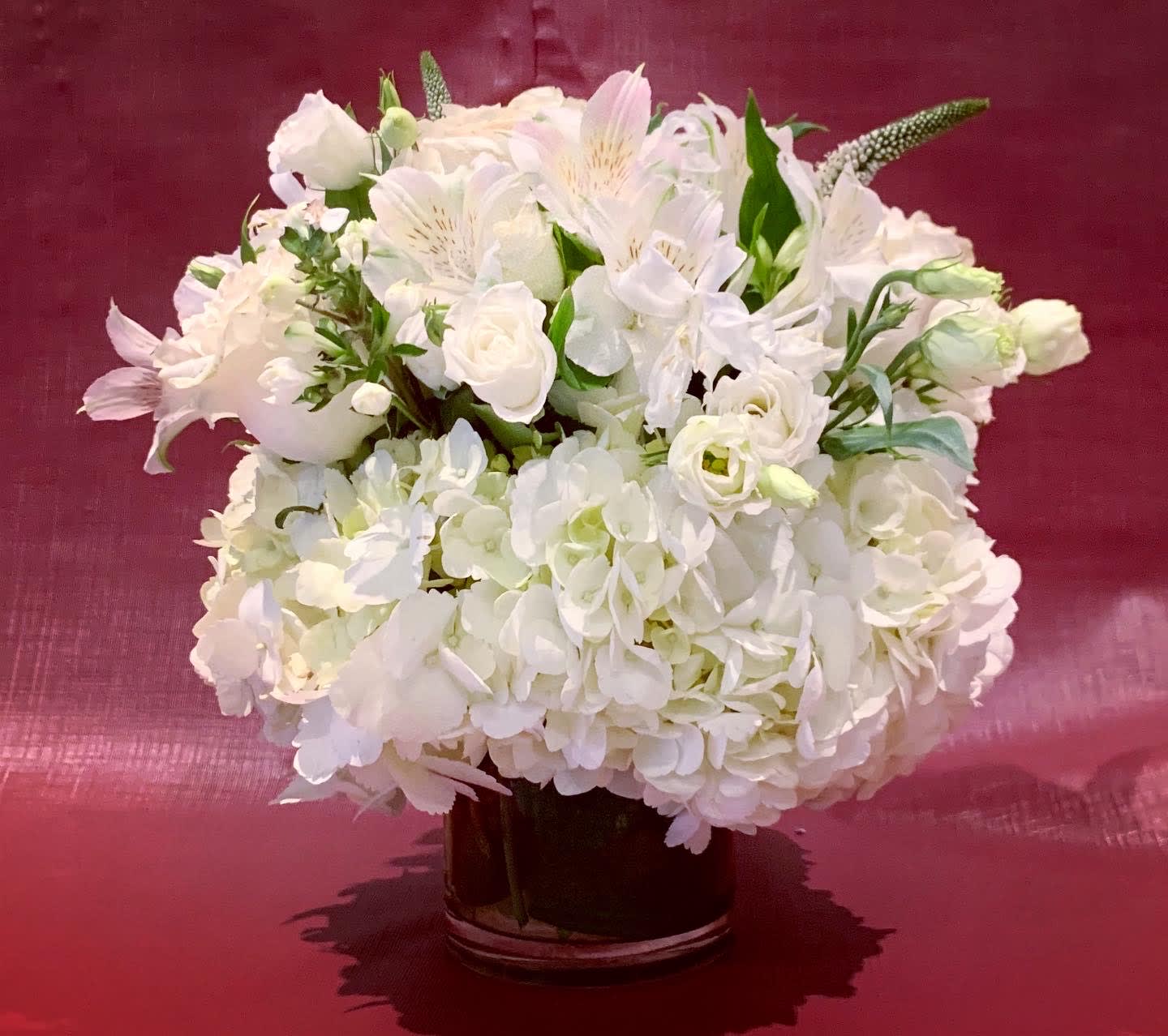 Custom Arrangement of white roses, white hydrangea &amp; white lisianthus  - Custom Arrangement of white roses, white hydrangea &amp; white lisianthus in clear glass cylinder with leaf wrap