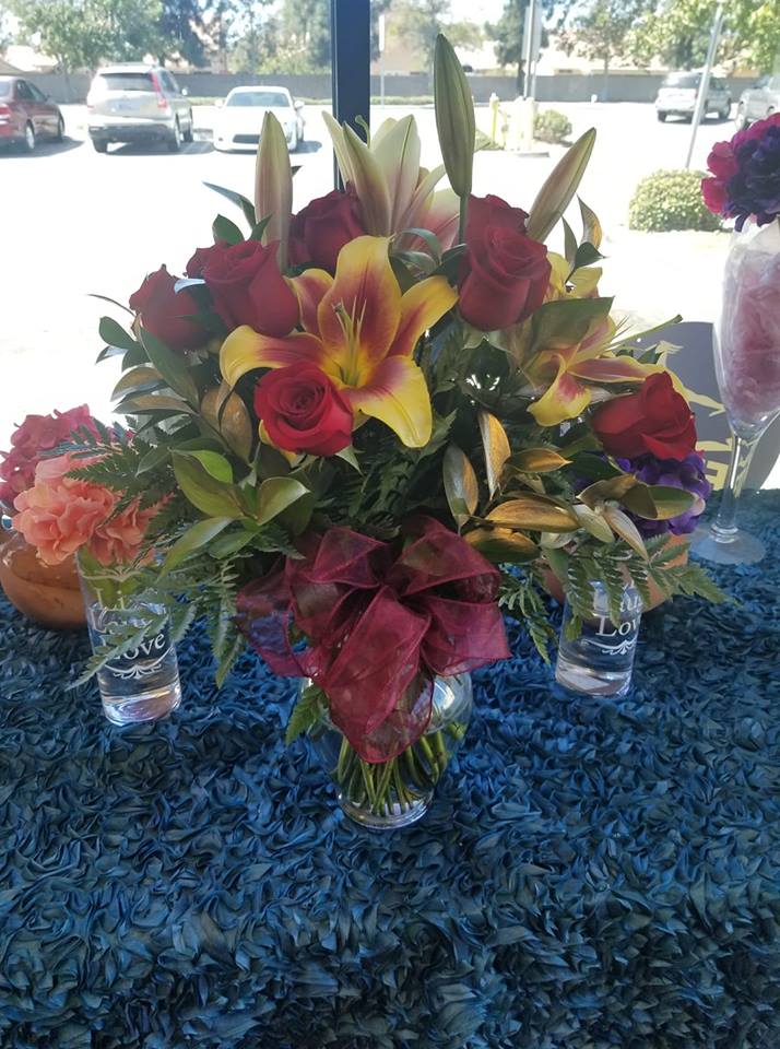 ROSES AND LILIES (DESIGNER CHOICE) ROSES AND LILIES (DESIGNER CHOICE) - 12 RED ROSES and 3 Lillie Stems (regarding the Lilies we usually have this color if not available we sub for white or peach color LILIES) we also include ruscus which we dye gold. this is about 24 to 26 inches tall. NOTE: DELUXE PRICE HAS 18 ROSES AND PREMIUM HAS 24 ROSES