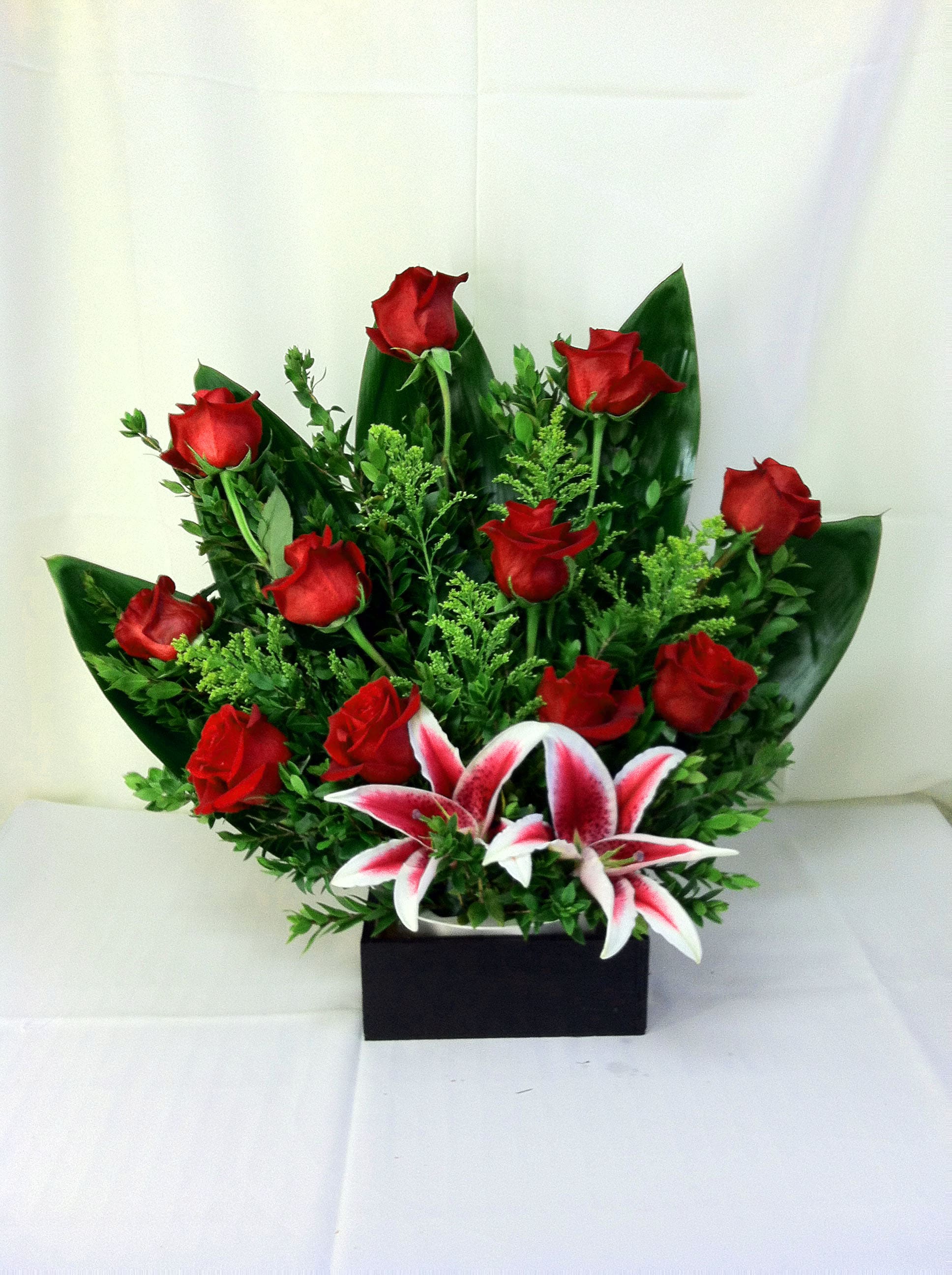 Flamingo's Flowers - Abundant Love - Cherish someone special by presenting a unique assortment of flowers and colors. Star gazers, red roses and greens are expertly designed in a wooded Box that is sure to warm hearts.