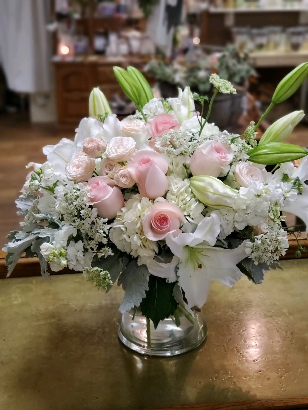Gentle Pastels  - Pink and white blooms for a soft look that include: hydrangea, lilies, roses, spray roses, stock &amp; dusty miller in a compact clear glass vase 