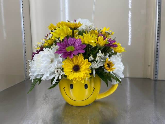 Just Smile - Mixed cut flowers in smiley face mug. With yellow daisies, white carnations, purple daisies, and an accent flower.