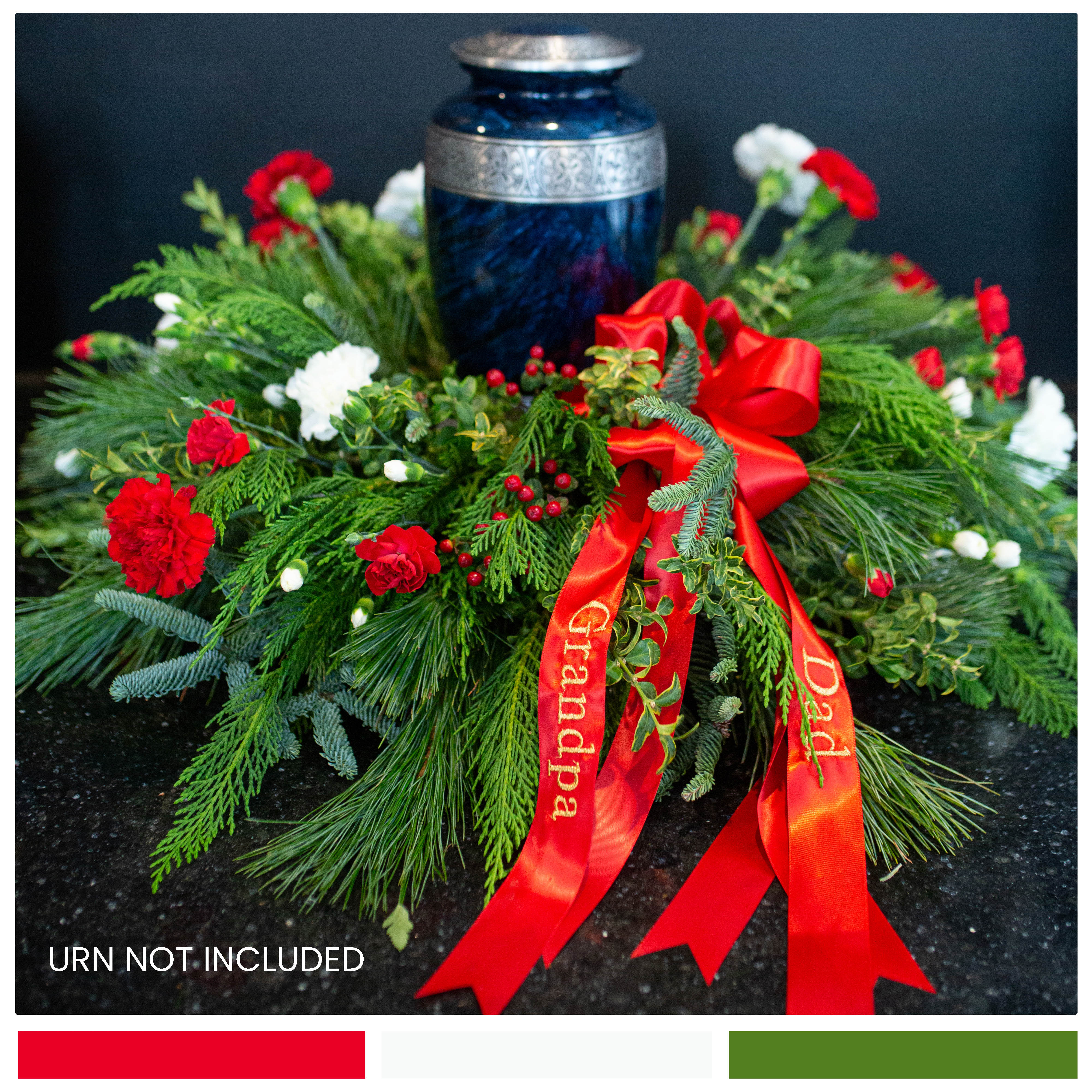 Winter Tribute Urn Surround Winter Tribute Urn Surround - A simple urn surround, filled with lush evergreens, carnations, and berries. A lovely tribute to your loved one's memory. Please note: Ribbons are custom embroidered for our families. If you'd like embroidered ribbons, please specify script or print letters, and the desired descriptors (Grandpa, Mom, Dad, etc.) in the special instructions. Please call us for further assistance if needed.