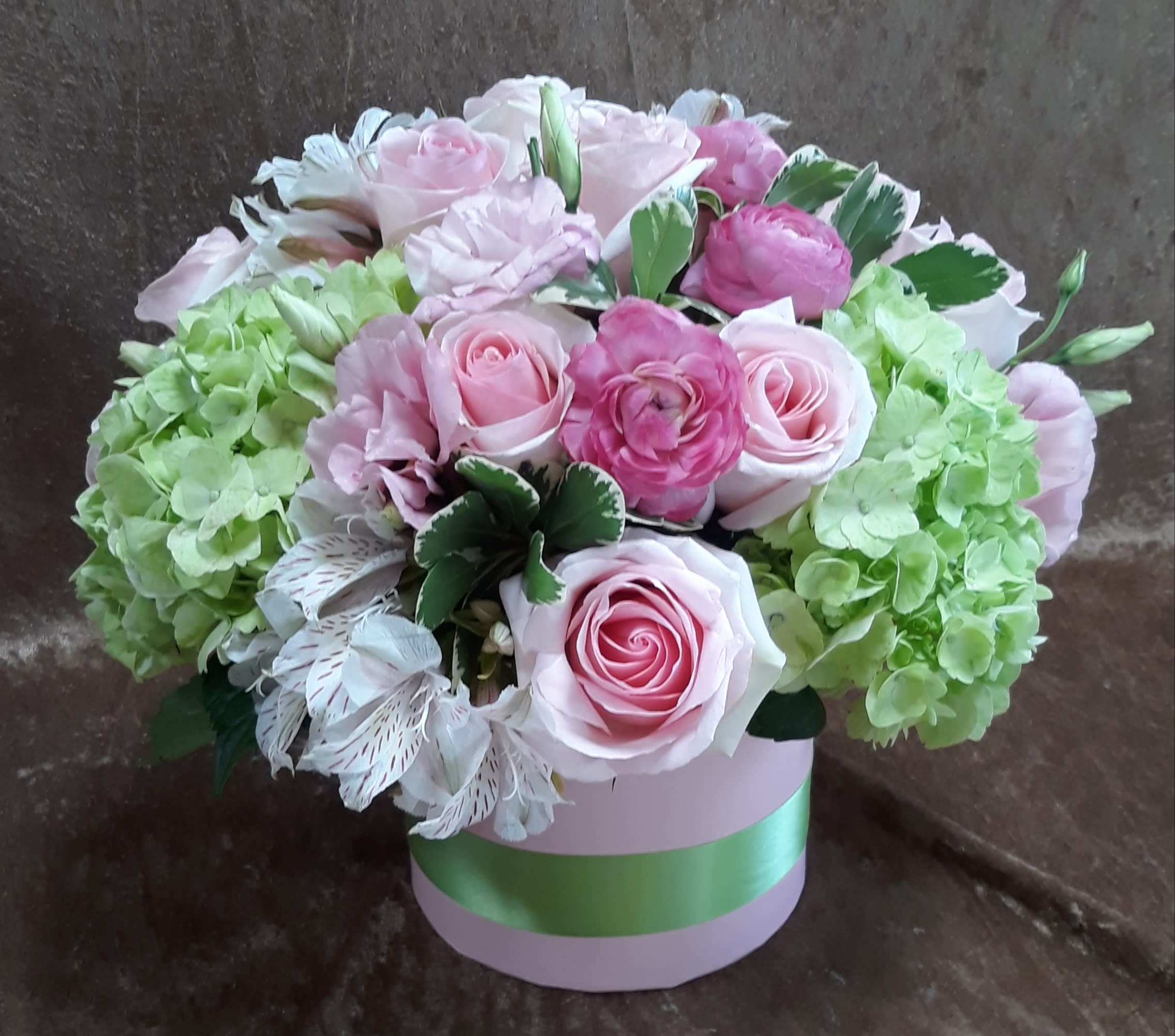 Pretty in Pink with Ribbon - SHOWN: Deluxe    Size: 12H x 12W Nothing says pretty like pink.  Roses, ranunculus, green hydrangea, alstroemeria and lisianthus in a keepsake hat box with RIBBON