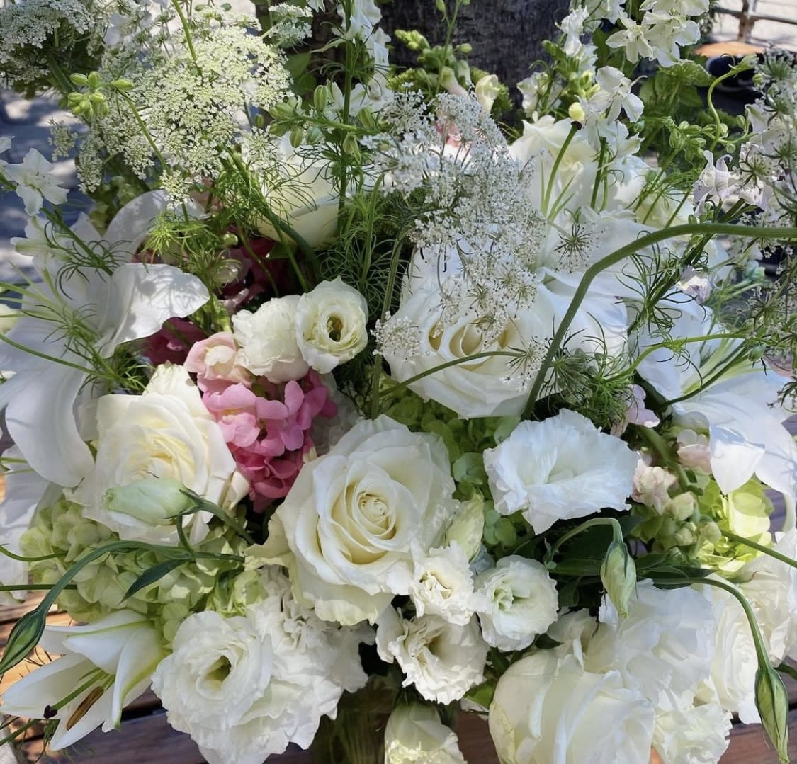 White with a Pop - This all white arrangement comes with a little pop of color featuring roses, lisianthus, snap dragons, lilies, hydrangea, Queen Anne’s lace and larkspur. Comes in a clear glass vase. 