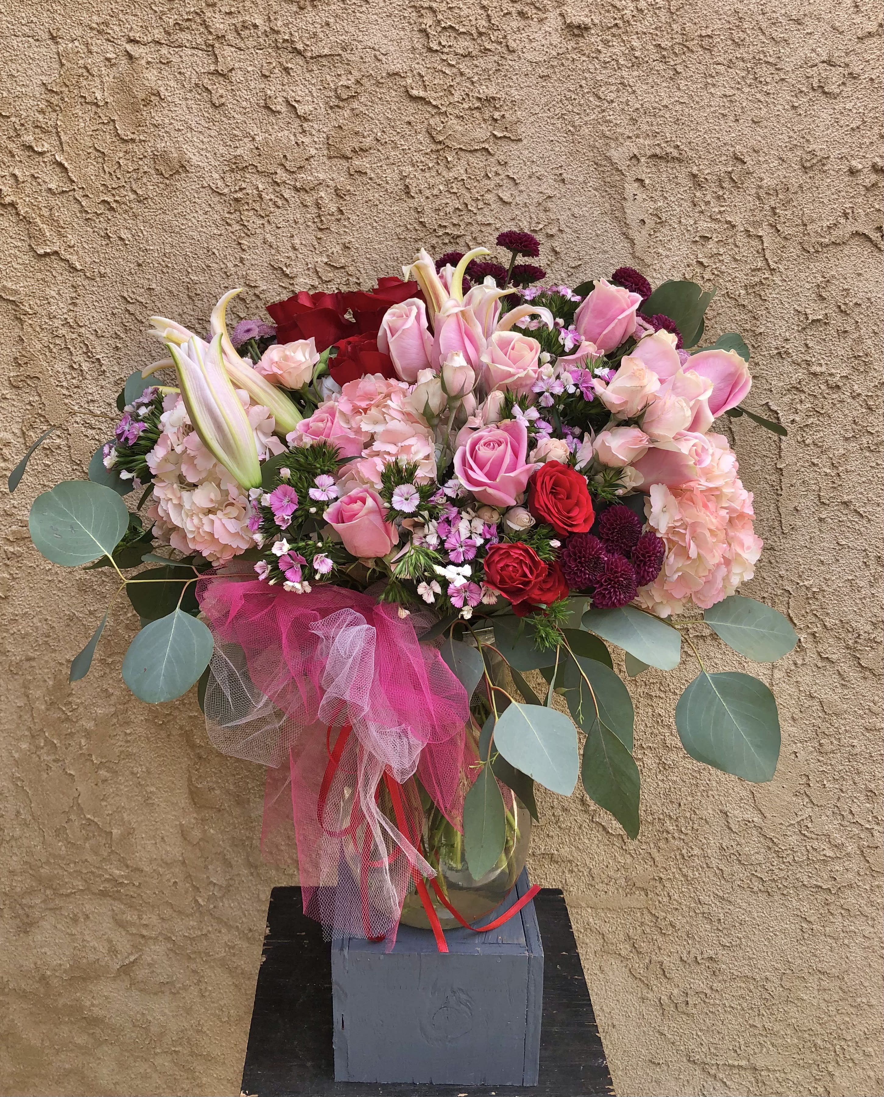 Here With Me - Beautiful pink and red arrangment featuring hydrangeas, large and spray roses, dianthus, baby mums, and lilies with green leaf accents. 
