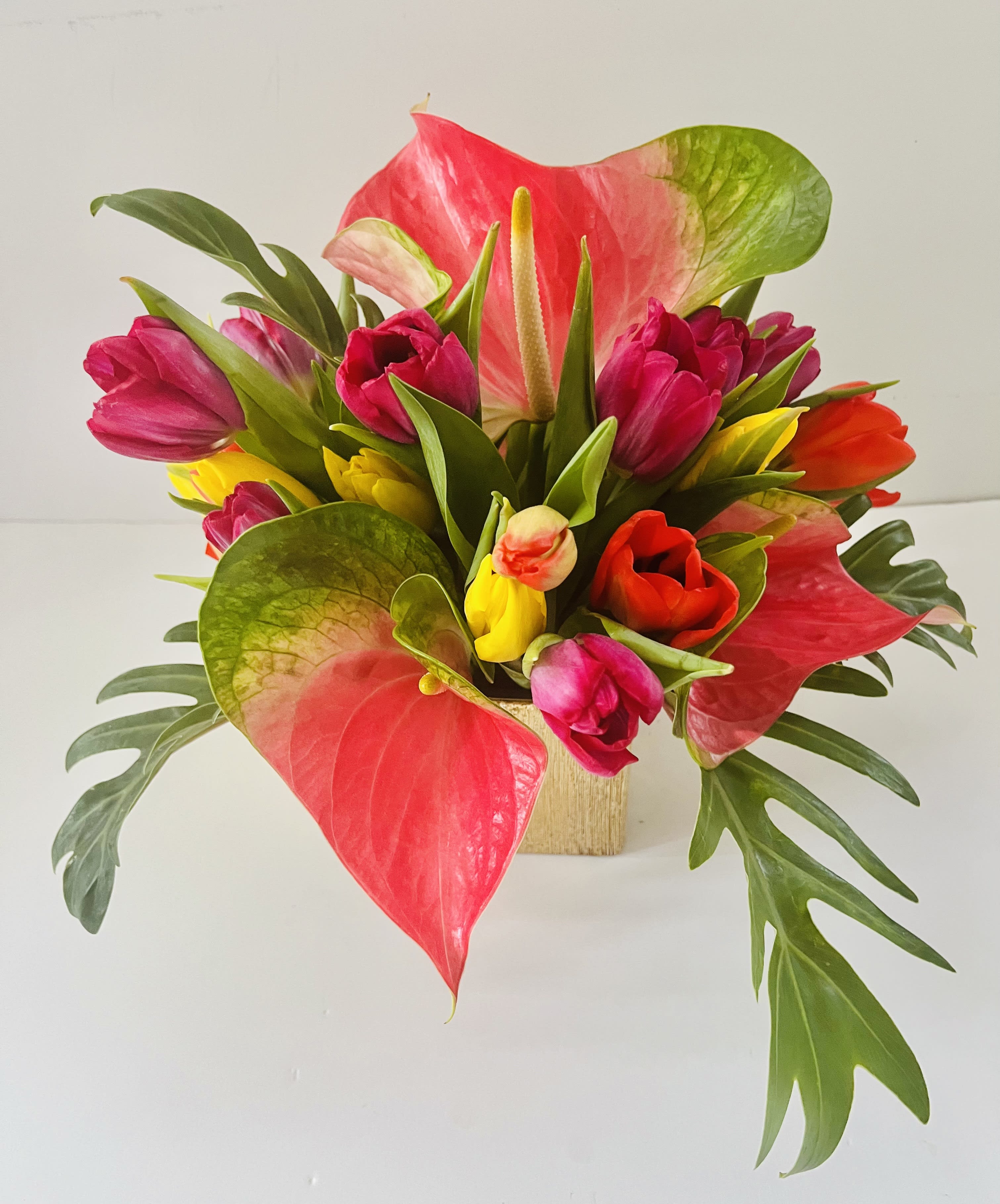 Tulips with a touch of tropicals - Tulips in assorted colors with a touch of tropical blooms (based on availability) in a designer choice container.  Designed to be viewed from all angles.  Enhanced option includes additional blooms and foliage.  All floral arrangments are designed to a style and use seasonal materials of varying content.  Please contact us directly for any custom orders or requests info@helemelebotanicals.com or 808.226.7667  We are committed to malama 'aina and strive to use locally sourced material, reduce packaging and reuse and recycle where possible. We will pick up any of our product (vessels, plants and floral supply material) when delivering a subsequent order. At that time, a $5 credit toward future purchase will be issued for each ceramic, metal or wood vessel returned.