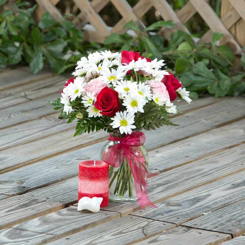 Live, Laugh, Love Live, Laugh, Love - Standard red and white bouquet with seven red roses, white daisies, and pink carnations in clear vase and red presentation bow.