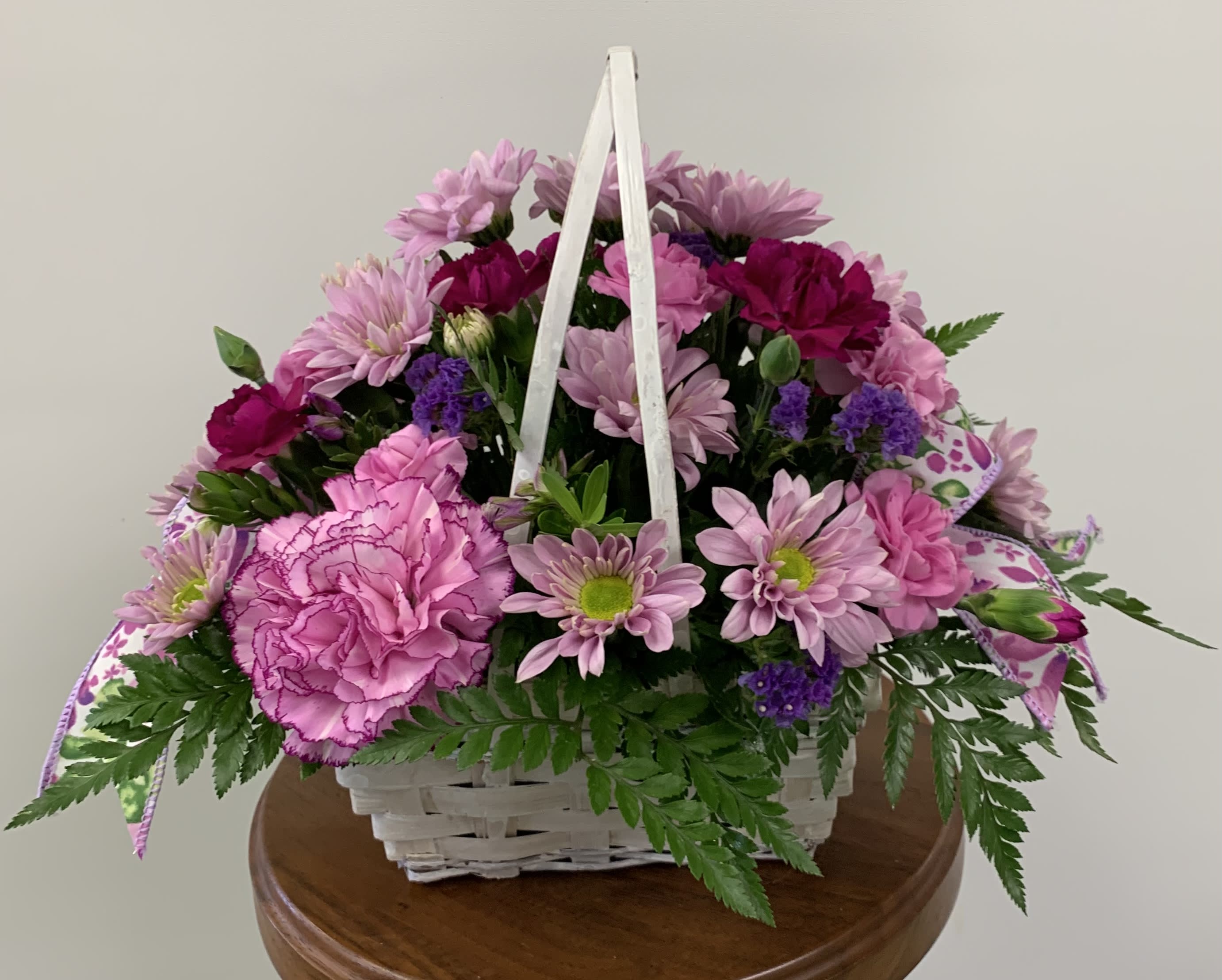 Daisy Daydreams - Get a handle on spring with this delightful array of floral favorites in a charming basket accented with lavender print ribbon. Surprise someone who could use a lift. It will make you both happy. Basket will includes a variety of purple and lavender blossoms. Orientation: All-Around  May include a touch of pink if all purples are not available. 